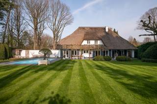 Op een zeer gegeerde en residentiële locatie in Essen-Heikant treffen we deze karaktervolle luxevilla, die in 2015 een renovatie onderging met duurzame en hoogwaardige afwerkingsmaterialen, en die zich in een perfecte staat van onderhoud bevindt.<br /><br />De entree geeft uit op de royale leefruimte op parketvloer. De living is ingedeeld in een gezellige zithoek en een eetkamer. Een sfeervolle gashaard vormt hierbij een centraal element tussen beide ruimtes.<br /><br />De leefkeuken is ingericht met alle hedendaagse apparatuur en beschikt tevens over een eetkamer.<br />Aansluitend op de keuken treffen we een bijkeuken en een kelder met aansluitingen voor de wasmachine en de droogkast. <br />Van hieruit is er toegang tot de dubbele garage met automatische toegangspoorten en een trap die (met traplift) leidt tot de fitnessruimte op de eerste verdieping. <br /><br />Links van de inkomhal komen we in een kantoor (eventueel gelijkvloers slaapkamer) met aansluitende badkamer die is voorzien van een ligbad, inloopdouche, dubbele lavabo en een toilet. <br /><br />Op de eerste verdieping geeft de zeer ruime overloop uit op de hoofdslaapkamer met dressing. <br />Verder zijn er nog drie ruime slaapkamers en een panic room. <br />De badkamer is ingericht met een douche en een enkele lavabo. <br />Ten slotte vinden we nog een apart nachttoilet.<br /><br />De woning is gebouwd op een ruim en lichtrijk perceel van ca. 2.643 m².<br />De zonnige tuin werd met de grootste zorg aangelegd met een vernieuwd terras (2022), een verwarmd zwembad met lounge en buitendouche en een koivijver.<br /><br />Algemeen:<br /><br />• Renovatie in 2015 met nieuwe keuken, vloeren, deuren,… met behulp van een binnenhuisarchitect.<br />• Het dak werd vernieuwd in 2025.<br />• Het terras werd vernieuwd in 2022.<br />• Beveiliging: Kogelvrij glas, 6 inbraakveilige deuren, alarminstallatie verbonden met de meldkamer en voorzien van een stil alarm.<br />• CV op stookolie met nieuwe ketel in 2021.<br />• Overal rolluiken.<br /><br />Deze villa is gelegen aan de Elzendreef, een zeer residentiële en rustige buurt in Essen-Heikant.<br />Er is een vlotte bereikbaarheid naar Antwerpen, Brussel en Nederland, zowel met de wagen als vanuit het treinstation van Essen.