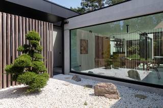 Discreet gelegen, helemaal achteraan de doodlopende wijk, ver weg van de Botermelkbaan, binnen een kleinschalig privédomein met slechts zes woningen, treffen we deze uitzonderlijke gelijkvloerse designvilla waar architectuur, licht en natuur op een bijzonder verfijnde manier samenvloeien.<br /><br />De woning ademt rust van bij de eerste aanblik. Strakke lijnen, royale glaspartijen, warme houtaccenten en een prachtig aangelegde tuin creëren een sfeer die tegelijk hedendaags, zacht en tijdloos aanvoelt. Hier geen overdaad, maar een ingetogen vorm van luxe: zuiver, doordacht en met oog voor elk detail.<br /><br />Gelijkvloers:<br />Binnen wordt het groen als het ware deel van het interieur. De leefruimte, eetplaats en keuken openen zich via grote raampartijen naar de tuin. De villa leeft rond licht, zicht en stilte. De aangelegde tuin met volwassen groen, beschutte terrassen, Japanse accenten en een bijzondere 110 jaar oude bonsai versterkt die bijna meditatieve beleving.<br /><br />De leefruimte vormt een elegante en open woonomgeving met zicht op de tuin en terrassen. Aansluitend vormt de keuken een uitgesproken architecturaal meubel: warme houttinten, zwarte accenten en een zwevend barmeubel zorgen voor een stijlvolle plek om te koken, te ontvangen en te leven.<br /><br />De master suite werd uitgewerkt als een private hotelbeleving. De slaapkamer sluit aan op een royale dressing en een bijzonder verfijnde badkamer met vrijstaand bad, dubbele lavabo, inloopdouche en zicht op een beschutte binnentuin. <br /><br />Daarnaast beschikt de villa over een volwaardige gastenkamer met eigen douche en toilet, waardoor gasten in alle comfort en privacy kunnen verblijven. <br /><br />Kelderverdieping:<br />De kelderverdieping bestaat uit 4 delen, te starten met een berging, een IT-/technische ruimte, een wasplaats en een extra troef: een echte private High-End-Cinema. Donkere materialen, subtiele lichtlijnen, een royale projectiewand en een hoogwaardige lounge-opstelling creëren een intieme bioscoopbeleving in eigen huis. <br /><br />Buitenbeleving:<br />Ook buiten is elk detail doordacht. De terrassen sluiten naadloos aan op de leefruimtes en bieden verschillende plekken om te ontspannen, te tafelen of in alle privacy van de tuin te genieten. Aan de voorzijde zorgt de overdekte parkeerzone met laadvoorziening voor een praktische en stijlvolle ontvangst.<br /><br />Deze villa is geen klassieke woning, maar een zorgvuldig gecreëerde leefomgeving. Een plek waar architectuur niet overheerst, maar rust brengt. Waar technologie discreet aanwezig is. En waar elke ruimte ontworpen werd om comfort, schoonheid en privacy op een uitzonderlijk niveau samen te brengen.<br /><br />Een unieke eigendom voor wie gelijkvloers, luxueus en discreet wil wonen in een groene residentiële omgeving nabij Schoten, ’s-Gravenwezel en de verbindingsassen richting Antwerpen.<br /><br />Bijzonderheden:<br />- Zuidoost georiënteerde tuin<br />- EPC-label A<br />- E-peil E10<br />- Loxone-domotica<br />- Luchtwarmtepomp<br />- Zonnepaneleninstallatie 36 panelen (14 kW)<br />- 16kW Thuisbatterij<br />- Laadpaal<br />- Camera’s binnen en buiten<br />- Automatische poorten<br />- Alarm met raam-, bewegings- en trillingsdetectie<br />- Triple glas / vierseizoensglas / Inbraakwerend<br />- Luidsprekers in elke kamer <br />- Hoogwaardige maatkeuken met Bora Professional, Quooker, Siemens koffiemachine, combi-oven, steamer en warmhoudlade<br />- Dubbele koelkast, dubbele diepvries en bijkomende koelkast<br />- Japans toilet<br />- Private cinema met native 4K-projectie en 26 luidsprekers<br />- Aangelegde tuin met Japanse accenten en 110 jaar oude bonsai