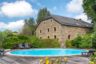 Midden in de prachtige natuur rond Malmedy bevindt zich deze karaktervolle natuurstenen hoeve, waar authenticiteit, ruimte en hedendaags comfort harmonieus samenkomen. Deze volledig gerenoveerde eigendom is ontworpen om grote gezinnen en groepen in alle comfort te ontvangen en vormt de ideale uitvalsbasis voor ontspannen verblijven, familiebijeenkomsten of vakanties met vrienden.<br /><br />De leefruimtes stralen warmte en gezelligheid uit dankzij de combinatie van authentieke materialen, zoals natuursteen, houten balken en bakstenen plafonds, met een eigentijdse afwerking. De ruime, volledig uitgeruste keuken is perfect afgestemd op grote gezelschappen en sluit naadloos aan op een royale eetruimte waar samen tafelen centraal staat. De gezellige woonkamer met open haard en biljart nodigt uit om te ontspannen na een actieve dag.<br /><br />De woning beschikt over 7 slaapkamers en 7 badkamers, waardoor elke gast kan genieten van comfort, privacy en een eigen ruimte. De kamers behouden hun landelijke charme en bieden tegelijk alle praktische voorzieningen voor een zorgeloos verblijf.<br /><br />Buiten strekt zich een mooi aangelegde tuin uit waar rust en natuur de hoofdrol spelen. Tijdens de zomermaanden zorgen het verwarmde buitenzwembad, de zonneterrassen, de barbecue en de verschillende zithoeken voor een heerlijke vakantiesfeer. In de winter krijgt de hoeve een totaal andere charme, met besneeuwde landschappen en een warme, gezellige ambiance.<br /><br />De wellnessruimte met sauna vormt de perfecte afsluiter van een dag wandelen of fietsen in de omliggende bossen, op het plateau van de Hoge Venen of in het nabijgelegen Nationaal Park Eifel.<br /><br />Een uitzonderlijk eigendom dat authenticiteit, comfort en een indrukwekkende capaciteit combineert. Ideaal als ruime familiewoning, tweede verblijf of kwalitatieve vakantie-accommodatie in één van de mooiste natuurgebieden van België.