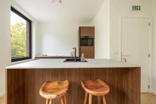 <p><span> </span></p><p><span>Strak gerenoveerd, energiezuinig én helemaal instapklaar: dit appartement van ca. 67 m² op de eerste verdieping heeft het allemaal. Je krijgt een heerlijk lichte leefruimte met open keuken, twee slaapkamers en een stijlvolle badkamer, afgewerkt in warme houttinten. En dat in een fijne buurt van Berchem, met het Brilschanspark en natuurgebied Wolvenberg op wandelafstand.</span><span> </span></p><p><span> </span></p><p><span>Lichte leefruimte met warme leefkeuken</span></p><p><span>Je komt het appartement binnen in de centrale hal, van waaruit je meteen doorloopt naar de leefruimte vooraan. Hier is lekker veel plaats voor een ruime zithoek en een grote eettafel. Het kamerbrede raam trekt veel natuurlijk licht binnen en de warme parketlaminaat loopt mooi door in het hele appartement. De zwarte pvc-ramen met driedubbele beglazing zorgen voor een strak accent én extra comfort.  De open keuken past perfect in dat plaatje. De donkerbruine houtlook kasten geven de ruimte warmte, terwijl het lichte werkblad en het donkere kraanwerk het geheel strak houden. Het grote kookeiland met spoelbak doet tegelijk dienst als gezellige ontbijtogen: ideaal om er een paar barkrukken bij te schuiven. Ook praktisch is alles voorzien, met Samsung-toestellen zoals een combioven en vaatwasser en een Elica inductievuur met ingebouwde afzuiging. </span></p><p><span> </span></p><p><span>Twee slaapkamers &amp; stijlvolle badkamer</span></p><p><span>Via de lange hal ga je naar de twee slaapkamers. De eerste is leent zich perfect als kinder-, logeer- of werkkamer. De master bedroom biedt ruim plaats aan een dubbel bed en extra kasten. Ook hier zorgen de grote ramen met driedubbele beglazing voor natuurlijk licht.  De badkamer sluit helemaal aan bij de rustige, hedendaagse stijl van het appartement. Je hebt er een ruime inloopdouche met grijze betegeling en regendouche, een zwevend houtlook meubel met witte opbouwwastafel en donker geborsteld kraanwerk. Het toilet is netjes geïntegreerd in dezelfde ruimte. In de hal vind je bovendien nog een aparte berging van met aansluiting voor je wasmachine. Hier zitten ook de elektrische Ariston-boiler en de Vaillant-omvormer van de privatieve zonnepanelen netjes uit het zicht. </span></p><p><span> </span></p><p><span>Groen wonen in Berchem</span></p><p><span>Hier combineer je stad en groen zonder moeite. Het Brilschanspark en het mooie natuurgebied Wolvenberg liggen op wandelafstand, en ook sportcentrum Het Rooi is vlakbij. Voor je dagelijkse boodschappen vind je supermarkten enkele straten verder. Zin in een koffie, restaurant of wat winkels? Dan sta je zo in Oud-Berchem, de Pulhofwijk of Groenenhoek.   </span></p><p><span>Ook energetisch zit je hier bijzonder goed. Het appartement haalt EPC A en is voorzien van privatieve zonnepanelen, elektrische verwarming, driedubbele beglazing en ventilatiesysteem C+. Voeg daar conforme elektriciteit en een asbestveilig attest aan toe en je hebt een appartement waar je zonder grote werken meteen je dozen kunt uitpakken. </span></p><p><span> </span></p><p><span> </span></p>