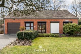 Voor meer info en foto’s, surf naar www.swevers.be – Op een centrale locatie in Heusden-Zolder vinden we deze knusse open bebouwing met een warme, huiselijke uitstraling. De gelijkvloerse woning werd gebouwd in 1970 en biedt een bewoonbare oppervlakte van ca. 138 m². Ze bevindt zich in een op te moderniseren staat, maar beschikt over een solide structuur en enkele reeds vernieuwde elementen zoals nieuwe ramen, dakisolatie, een zonneboiler en een conforme elektrische installatie.<br />Via de inkomhal bereikt u de lichtrijke woonkamer van 28,50 m², die het hart vormt van de woning en biedt voldoende plaats voor een gezellige zit- en eetruimte. Grote raampartijen zorgen voor veel natuurlijke lichtinval en een aangenaam zicht op de tuin. Aansluitend ligt de keuken van 7,20 m², die mogelijkheden biedt om naar eigen smaak te vernieuwen of eventueel open te werken. Naast de keuken bevindt zich een praktische berging/wasplaats, grenzend aan de inpandige garage van 15 m². Via de nachthal bereikt u drie slaapkamers van respectievelijk 12 m², 10,50 m² en 8,80 m², een badkamer en een apart toilet.<br />Het perceel van 761 m² met zuidwestelijke oriëntatie biedt een aangename tuin waar u volop van de zon kan genieten. Dankzij het omliggende groen is het hier heerlijk wonen. Tegelijk bevindt de woning zich op een gunstige locatie: de snelweg ligt op 3,5 km, winkels, scholen en horeca op ongeveer 2 km en openbaar vervoer op slechts 300 meter.<br />Deze woning vormt een uitstekende kans voor wie op zoek is naar een charmante thuis met potentieel op een centrale locatie. Voor meer informatie, bel 011 255 155. Bron bewoonbare oppervlakte: EPC – verslag.