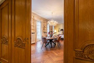 <p><strong>Deze uitzonderlijke villa is gelegen op een perceel van ca. 4.950 m² langs de Antwerpsesteenweg in Vosselaar en combineert aanzienlijke volumes met een doordachte indeling. De royale inkomhal biedt toegang tot de leefruimtes, bestaande uit een eet- en zithoek, een afzonderlijke tv-kamer en een bureauruimte. Centraal bevindt zich de vernieuwde keuken met Gaggenau-toestellen, uitgevend op het overdekte binnenzwembad, een lichtrijke leefruimte met tuincontact en een wellnessgedeelte met sauna. Verder beschikt de woning over een inpandig duplex appartement met eigen ingang, een totaal van acht slaapkamers en zes badkamers. </strong><br /><br /><strong><span>Indeling</span><br /></strong>Via de imposante entreehal betreedt u de woning. Aan de linkerzijde bevindt zich een eerste leefruimte die is ingericht met eet- en zitgelegenheid. Aansluitend volgt een afzonderlijke tv-kamer, met daarnaast een bijkomende ruimte die zich leent tot gebruik als bureau of werkkamer.</p>
<p>Het hart van de villa is de keuken, welke zich centraal in de villa bevindt. De keuken werd enkele jaren geleden vernieuwd en is uitgerust met kwalitatieve Gaggenau-toestellen. De keuken kijkt uit op het overdekte binnenzwembad en op een aangrenzende, lichtrijke ruimte met glazen dak, ingericht als eet/leefruimte en in direct contact met de tuin. De keuken alsook de ruimte met binnenzwembad verlenen toegang tot de kelderverdieping. Deze heeft een gedeeltelijke barfunctie en een wellnessfunctie, compleet met sauna en douches.</p>
<p>Verder op het gelijkvloers bevinden zich een vestiaire, een gastentoilet en een wasplaats. Vanuit de wasplaats is er toegang tot de ruime garage, voorzien van meerdere poorten aan voor- en achterzijde.<br /><br /><strong><span>Verdieping</span></strong><br />Op de eerste verdieping, dewelke we bereiken via de royale wenteltrap, bevinden zich drie slaapkamers, elk met bijhorende badkamer. De mastersuite, met royale afmetingen, is uitgerust met twee dressings. De tweede verdieping omvat nog twee bijkomende slaapkamers, een speelkamer, een extra badkamer en zolderruimte.<br /><br /><strong><span>Appartement</span></strong><br />In het pand is tevens een volwaardig inpandig appartement ondergebracht, opgevat als duplex en geschikt voor conciërge of inwonende ondersteuning. Dit appartement beschikt over een leefruimte, keuken, 2 badkamers en 3 slaapkamers, en functioneert autonoom binnen het geheel met eigen ingang.</p>
<p>De villa beschikt in totaal over 8 slaapkamers en 6 badkamers, en biedt een bewoonbare oppervlakte van ca. 1.436 m² (inclusief appartement). Het geheel wordt omgeven door een ruim, groen perceel dat privacy en rust waarborgt, met behoud van een vlotte bereikbaarheid.</p>
<p>Een eigendom met aanzienlijke volumes en diverse gebruiksmogelijkheden, geschikt voor wie ruimte, comfort en een zekere autonomie binnen het wonen weet te waarderen. Verder biedt de woning nog de mogelijkheid voor andere invullingen, zoals bv. B&B, kleinschalig restaurant, kantoor (bv. private banking) of een andere, rustige, zelfstandige activiteit.<br /><br /><span><strong>Bijzonderheden:</strong></span><br />- Riant perceel van ca. 4950m<span>²</span><br />- Totaliteit van 8 slaapkamers en 6 badkamers<br />- Indoor zwembad met welness<br />- Royale ruimtes met doordachte indeling<br />- Gunstige ligging nabij invalswegen en vlotte bereikbaarheid naar zowel Nederland als Antwerpen.</p>