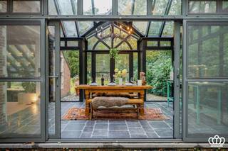 <p><span>Rustig gelegen verrassend ruime en hip ingerichte villa met o.a. grote leefruimte, bureel, 4 slaapkamers, 2 badkamers en dubbele inpandige garage omgeven door een ruime en lichte tuin van ca. 4.475 m².</span></p><p><span> </span></p><p><span>Gelijkvloers:</span></p><p><span>Inkomhal met vide op een tegelvloer met vestiairehoek en gastentoilet met handenwasser. Dubbele deuren naar de grote living onderverdeeld in een verhoogde zitkamer met openhaard, een eetplaats en aparte verlaagde bureelruimte. Aansluitend een aangename lichte oranjerie op een arduinenvloer met toegang tot de tuin en terras. De leefruimtes genieten veel lichtinval door de ramen rondom. </span></p><p><span>Vanuit de leefruimte en de inkomhal toegang tot de moderne en luxe keuken op natuurstenen vloer met kookeiland uitgerust met o.a. een dubbele spoelbak, combi stoom/heteluchtoven, combi hete lucht/microgolfoven, hete lucht-oven, 2 apothekerskasten, microgolfoven, vaatwasser, inductie kookplaat, ingemaakte dampkap en Amerikaanse koelkast. De keuken geniet veel lichtinval en een mooi zicht op de tuin dankzij de grote schuifdeur naar het terras. Aanpalende voorraadruime met airco. Verder is er een bijkeuken/wasplaats. Inpandige dubbele garage met automatische poorten en ingemaakte kasten. De CV-installatie en elektra zijn hier ook ondergebracht. </span></p><p><span><br />1e verdieping: </span></p><p><span>Via een houten trap toegang tot de nachthal op de eerste verdieping op laminaatvloer. Masterunit bestaande uit een grote slaapkamer en een moderne badkamer met een inloopdouche, lavabo en wc. Verder op deze verdieping nog 3 ruime slaapkamers waarvan 1 met een vaste trap naar de zolderverdieping en 1 opgedeeld in twee (slaap)kamers of bureel met slaapkamer.  2e badkamer uitgerust met o.a. douche, toilet en dubbele lavabo. </span></p><p><span><br />Zolderverdieping:     </span></p><p><span>Via een vaste trap in een van de slaapkamers toegang tot de grote zolderruimte op betonvloer welke eventueel nader ingericht kan worden. </span></p><p><span><br />Kelderverdieping: </span></p><p><span>Middels een trap vanuit de bergruimte toegang tot de bergkelder. </span></p><p><span><br />Tuin: </span></p><p><span>Mooi aangelegde en goed onderhouden tuin, volledig omheind met automatische toegangspoort. Ruim terras aan de achterzijde van het huis, deels overdekt. Aan de voorzijde een oprit, carport en ruime parking in kasseien.</span></p><p><span> </span></p><p><span>Bijzonderheden:</span></p><ul><li><span>Verwarming middels warmtepompen en mazout installatie.</span></li><li><span>Camerabewaking en alarminstallatie (binnen en buiten)</span></li><li><span>Zeer rustig in het groen gelegen nabij Heide-Kalmthout en Putte–Kapellen.</span></li><li><span>Zeer degelijk gebouwd en goed onderhouden.</span></li><li><span>Moderne luxe keuken</span></li></ul><p><span> </span></p><p><span> </span></p><p><span> </span></p><p><span> </span></p>