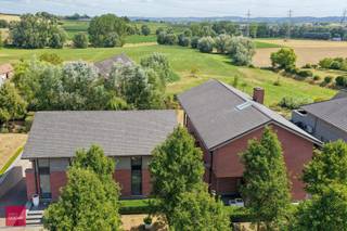 Inkomhal, living, ingerichte keuken met eiland, 3 slaapkamers (eventueel 4de slaapkamer mogelijk), 2 badkamers, dressing, bureelgebouw (of 2de woning, zorgwoning...) bestaande uit: Inkomhal met afzonderlijke ingang, 3 burelen met alle voorzieningen (ingemaakte kasten, kabelvoorzieningen...), wachtplaats, vergaderruimte, keuken (professioneel gedeelte ca 200m²). Verder is de villa volledig onderkelderd (mancave, wijnkelder, dubbele garage) en is er een parking, zonnige terrassen en zuidgerichte tuin met prachtig verzicht.