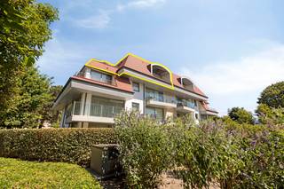 <u><em><strong>Exclusief dakappartement met royale zonneterrassen in Residentie Elzenhof</strong></em></u><br /><br />Op een uitzonderlijk rustige ligging, midden in het groen en aan de rand van de gegeerde Dumontwijk, bevindt zich dit unieke dakappartement in de stijlvolle Residentie Elzenhof. Op slechts 250 meter van het strand en op wandelafstand van het bruisende centrum geniet u hier van een zeldzame combinatie van privacy, comfort en een absolute toplocatie.<br /><br />Bij het betreden van het appartement wordt u verwelkomd in een verzorgde inkomhal met gastentoilet. De royale leefruimte baadt de hele dag in natuurlijk licht dankzij de grote raampartijen en vormt samen met de afzonderlijke keuken een aangename en uitnodigende leefomgeving.<br /><br />De zuidoost oriëntatie zorgt voor een optimale bezonning, waardoor u van 's morgens tot zonsondergang kunt genieten op de twee prachtige terrassen die naadloos aansluiten op de leefruimte. Een unieke buitenbeleving waar rust en privacy centraal staan.<br /><br />Het appartement beschikt over twee ruime, volwaardige slaapkamers, waarvan één rechtstreeks uitgeeft op het zonovergoten terras. De stijlvolle badkamer is smaakvol ingericht met een ruime inloopdouche, een elegant lavabomeubel en een tweede toilet.<br /><br />Een absolute meerwaarde vormt het uitzonderlijk ruime terras, voorzien van vier praktische bergingen. Eén ervan beschikt over een aansluiting voor een wasmachine, terwijl de overige bergingen royale extra opbergruimte bieden.<br /><br />In de ondergrondse verdieping bevindt zich bovendien een ruime privatieve kelderberging, ideaal gelegen vlak bij de lift. Daarnaast beschikt de residentie over een gemeenschappelijke fietsenberging.<br /><br />Dit exclusieve dakappartement vormt de perfecte keuze als stijlvolle vaste woonst of als luxueus tweede verblijf aan zee. Een unieke opportuniteit voor wie op zoek is naar ruimte, rust, comfort en een zorgeloze woonervaring op een van de meest gegeerde locaties van De Panne.<br /><br />Er bestaat de mogelijkheid tot aankoop van een ruime ondergrondse garage. Deze biedt niet alleen plaats aan een wagen, maar beschikt tevens over voldoende extra ruimte voor fietsen, strandmateriaal of bijkomende stockage. Vraagprijs: €67.500<br /><br />Met de installatie van een warmtepomp kan het appartement een gunstig EPC-label B behalen (158 kWh/m² jaar).