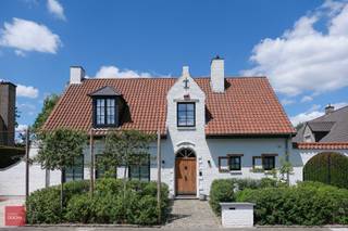 Inkom met gastentoilet en vestiaire, ruime living met parket, open haard en ingebouwkasten, eetkamer met parket, luxueus ingerichte keuken met...