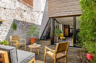 Charme en karakter<br /><br />Deze hedendaagse herenwoning in Antwerpen combineert karakter met behoud van authentieke elementen, die haar een unieke uitstraling geven. Je betreedt de woonst via een statige inkomhal met hoge plafonds en originele trap. Op het gelijkvloers vind je een ruime, inpandige garage, geschikt voor je wagen, fietsen en extra opslag. Deze garage biedt plaats aan één voertuig en heeft een laadpaal. Vanuit de hal bereik je via de tuinkamer een prachtige, zonnige stadstuin. Deze verdieping biedt ook toegang tot een droge kelder voor extra opslagruimte.<br /><br />Deze woonst is ingedeeld als een stijlvolle bel-etage. Op de eerste verdieping ontdek je een volledig ingerichte keuken die naadloos overgaat in de lichtrijke eet- en leefruimte. Grote raampartijen zorgen hier voor veel natuurlijk licht en een aangenaam ruimtegevoel. Via de buitentrap heb je tevens directe toegang naar de tuin. De tweede verdieping huisvest een ruime badkamer met ligbad, douchecel, wastafel en een toilet. Op dit verdiep bevindt zich ook de eerste ruime slaapkamer. In totaal telt de woonst drie slaapkamers. De bovenste verdieping is voorzien van twee slaapkamers, waarvan één momenteel als bureau is ingericht.<br /><br />Deze instapklare woning combineert authentieke charme met moderne gemakken en is te koop in Antwerpen. De woonst is energiezuinig en heeft een EPC-label B en beschikt over acht zonnepanelen met 10kWh thuisbatterij met gekoppeld Energy Management System voor optimaal verbruiksregeling wat bijdraagt aan een laag energieverbruik doorheen het gehele jaar. De woning heeft een lucht-lucht warmtepomp die zorgt voor een aangename warmte en verkoeling op warme dagen.<br /><br />Centraal ligging<br /><br />Je woont hier op een uitstekende locatie in Antwerpen, waar alle voorzieningen zich binnen handbereik bevinden.