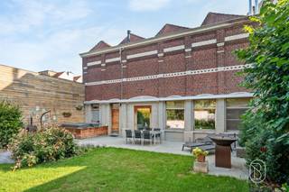 In het centrum van Ronse bevindt zich deze uitzonderlijke eigendom, bestaande uit twee afzonderlijke wooneenheden. De statige voormalige directeurswoning combineert authentieke architectuur en karaktervolle elementen met royale volumes, hedendaags wooncomfort en tal van mogelijkheden.Wijnstraat 44 – karakter, ruimte en grandeur:Via de ruime, overdekte galerij met plaats voor twee wagens bereikt u de imposante herenwoning. Hoge plafonds, sierlijsten, authentieke vloeren en karaktervolle schouwen springen meteen in het oog.Op het gelijkvloers bevinden zich verschillende ruime leef- en ontvangstruimtes. Dankzij hun indeling lenen deze zich uitstekend voor wie wonen en werken wil combineren, bijvoorbeeld als kantoor, praktijkruimte of voor de uitoefening van een vrij beroep.Achteraan bevindt zich een afzonderlijke leef- en zitruimte met zicht op de groene stadstuin, met aansluitend de ingerichte keuken. Zo kunnen professionele en private ruimtes mooi van elkaar gescheiden worden.De eerste en tweede verdieping omvatten samen vijf slaapkamers en twee badkamers. Daarnaast is er op de eerste verdieping, bereikbaar via een aparte trap, een grote polyvalente ruimte, ideaal als atelier, hobbyruimte, praktijk, kantoor of extra leefruimte. Ook een praktische (wijn)kelder is aanwezig.De prachtige stadstuin vormt een oase van rust en privacy. Het ruime terras en de jacuzzi maken het geheel compleet.Technisch:- Conforme elektrische installatie- EPC-label D- 36 zonnepanelen, geplaatst na opmaak van het EPC-attest en dus nog niet meegerekend- Regenwaterput- Laadpaal- Centrale verwarming op stookolie (conformiteitskeuring aanwezig)- Airconditioning in bepaalde slaapkamers- WaterverzachterWijnstraat 42 – investeringseigendom:Het tweede gedeelte is een afzonderlijke, recent gerenoveerde woning met eigen toegang. Op het gelijkvloers bevinden zich een woon- en leefruimte, keuken, bureau/slaapkamer en koertje. De eerste verdieping telt twee slaapkamers.De woning is momenteel verhuurd voor € 775/maand op basis van een jaarcontract en biedt zo een onmiddellijke huuropbrengst.Een zeldzame eigendom, ideaal voor een groot gezin, vrij beroep, wonen en werken, kangoeroewonen of de combinatie van eigen bewoning en verhuur.Een unieke combinatie van grandeur, wooncomfort en opbrengstpotentieel in hartje Ronse.Graag meer info en een bezoek? Caroline@immobeguin.be