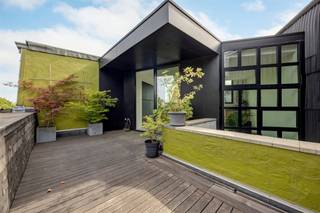 <p><span>Achter deze prachtige eclectische gevel gaat een woning schuil die je onmogelijk vanop straat kunt inschatten. Wat ooit een klassieke stadswoning was, groeide door een doordachte renovatie uit tot een unieke architecturale thuis waar licht, ruimte en beleving centraal staan. Dankzij de speelse split-levelindeling, de centrale patio, het royale dakterras en de indrukwekkende leefkeuken voelt elke verdieping anders aan, terwijl het geheel één harmonieus verhaal vormt. Een zeldzame woning voor wie houdt van karakter, design en wonen met</span><span> </span><span>een eigen identiteit.</span></p><p><span> </span></p><p><span> </span></p><p><span>Architectuur die je stap voor stap ontdekt</span><span><br />Van zodra je de dubbele voordeur opent, merk je dat dit geen doorsnee stadswoning is. De brede inkomhal baadt in het daglicht dankzij de hoge ramen aan beide zijden van de woning. De tweede inkom achteraan is bijzonder praktisch en de ruimte kan perfect multifunctioneel ingezet worden, als werkruimte/ fietsenberging/ atelier,… je vindt er ook de technische ruimte terwijl een aparte wasruimte en de kelder het dagelijkse comfort compleet maken.<br />Wat deze woning echt bijzonder maakt, is de manier waarop de verschillende niveaus met elkaar verbonden zijn. Geen lange donkere gangen of afgesloten verdiepingen, maar een speelse circulatie waarbij je telkens nieuwe zichten krijgt op de woning. De centrale patio brengt het daglicht tot diep in het huis en zorgt ervoor dat de verschillende leefruimten voortdurend met elkaar in verbinding staan.<br />De eerste verdieping is volledig ingericht als slaapverdieping. De master bedroom vormt een rustige privésuite met een ruime dressing en een ensuite badkamer. Daarnaast zijn er nog twee slaapkamers met zicht op het groen en een tweede douchekamer.</span></p><p><span> </span></p><p><span>Leven op verschillende niveaus</span></p><p><span>De tweede verdieping vormt een heerlijke overgang. De lichte zitkamer kijkt uit op het groen en sluit aan op een gezellige tv-hoek. Daarnaast bevindt zich een bureau op maat met ingemaakte kasten. Centraal ligt een patio die het natuurlijke licht diep de woning in trekt en een bijzonder gevoel van openheid creëert.<br /><br /></span></p><p><span>Een keuken waar het leven zich afspeelt</span></p><p><span>Helemaal boven bevindt zich de leefkeuken van ongeveer 30 m². De maatwerkkeuken met natuurstenen werkblad, Lacanche-gasfornuis, Quooker, grote koelkast en veel kastruimte vormt het kloppende hart van de woning. Via de grote schuiframen stap je naar het oostgerichte dakterras van 17 m² met zicht op de boomkruinen.</span></p><p><span> </span></p><p><span>Een buurt waar je graag thuiskomt</span><span><br />De Stanleystraat ligt op de grens van Oud-Berchem, Zurenborg en het Groen Kwartier. 's Morgens wandel je naar Polly voor een specialty coffee of spreek je af bij Café Service op de hoek van de straat. Station Antwerpen-Berchem, winkels, restaurants en openbaar vervoer liggen allemaal op wandelafstand.</span></p><p><span> </span></p>