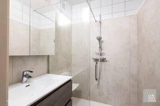 <strong>Indeling</strong><br /><br /><span>De afgesloten garage is zowel via de lift als een gemeenschappelijke poort bereikbaar. </span><br /><br /><span>De ruime inkomhal met vestiaireruimte en gastentoilet biedt toegang tot de leefruimte, overdekt terras, gesloten keuken en berging. Via de aangrenzende nachthal zijn de badkamer en de twee slaapkamers bereikbaar</span><span>.</span><br /><br /><strong>Afwerking</strong><br /><br /><span>De keuken is geïnstalleerd in een geheel van onder- en bovenkasten, spoeltafel, oven, microgolf, vitrokeramische kookplaat en dampkap, koelkast met vriesvak.</span><br /><br />De recent gerenoveerde badkamer is voorzien van een badmeubel, inloopdouche en natuurlijke ventilatie.<br />
<div><span> </span></div>