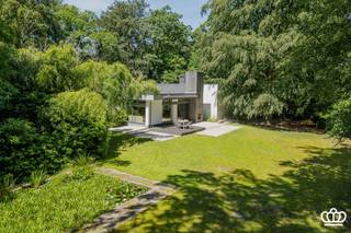 <p><span>Modernistische design villa, prachtig en residentieel gelegen te Kapellen, met 3 / 4 slaapkamers, 2 badkamers en inpandige garage op een mooi en open perceel met veel privacy van 6.355 m². </span></p><p><span>INDELING</span></p><p><span>Gelijkvloers:<br />Het gehele huis heeft een typisch zeer open en licht karakter, alle leefruimtes staan in open verbinding met elkaar en rondom voorzien van grote raampartijen die vrij uitzicht bieden over de prachtige tuin.</span></p><p><span>Inkomportaal met ingebouwde bloembak op wit marmer, overgaande in de inkom met vestiairehoek en gastentoilet. Inkom gaat over in een bilbliotheek / tv hoek op marmer met inbouwkasten, aansluitend zithoek met openhaard op parket, door een klein niveau verschil overgaand in een salon en eetkamer op parket en aanpalende open keuken voorzien van alle hedendaagse inbouwapparatuur en natuurstenen werkblad.    </span></p><p><span>Verdieping + 1/2:<br />Via een open trap toegang tot de galerij op de halve verdieping die uitgeeft op een masterbedroom bestaande uit slaapkamer, dressing en badkamer uitgerust met ligbad, douche, toilet, bidet en 2 lavabo’s. Verder nog 2 slaapkamers die een 2e badkamer delen, voorzien van ligbad, douche, toilet, bidet en 2 lavabo’s. De gehele verdieping, met uitzondering van de badkamers, is op tapijt.</span></p><p><span>Verdieping -1/2:<br />Middels dezelfde open trap toegang tot een gang die uitgeeft op de inpandige garage voor 2 wagens met automatische poort en aansluitingen voor wasmachine en droger. Een bergkamer, momenteel in gebruik als strijkkamer, een stookruimte en een atelierruimte welke eventueel is in te richten als extra (slaap)kamer met mogelijke doucheruimte. Achter inkomhal met toilet en toegang tot de kelder. </span></p><p><span>Kelder:<br />De gehele leefverdieping is onderkelderd, bestaande uit een betegeld deel met een wijnkelder en voorraadkelder.  Via een doorgang toegang tot de onafgewerkte bergkelder (122 m²). </span></p><p><span>Tuin:<br />Volwassen parktuin met fraaie bomenstand, rondom de villa zijn diverse terrassen, deels te overdekken met groot zonnescherm, vijver/waterpartij in het terras. In de tuin bevindt zich een ouder zwembad dat momenteel is omgevormd tot een vijver. De geniet volledige privacy en veel zoninval rond de villa. </span><span>In de tuin bevinden zich nog 2 houten tuinbergingen.</span></p><p><span>Overig / Bijzonderheden:<br />-Villa in fraaie seventies design stijl<br />-Bijzonder mooi gelegen in een residentiele wijk nabij het dorpscentrum van Kapellen met winkels, scholen, treinstation, ...<br />-De villa heeft veel potentieel maar is aan renovatie toe.<br />-CV op mazout</span></p><p><span> </span></p><p><span> </span></p>