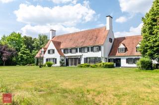 Villa gelegen op perceel van +/- 9.600m², bestaande uit inkomhal, bureel, living, eetplaats, keuken, bijkeuken (wasplaats), dagelijkse woonkamer (tv-kamer), dubbele garage, 5 slaapkamers, 3 badkamers, dressing, ruime zolder met vaste trap, kelders, terrassen, berging en zuidgerichte tuin. Mogelijkheid +/- 2ha landbouwgrond bij te kopen.<br />