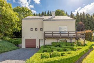 <p><span>Deze ruime woning is gelegen in een groene en rustige omgeving in Nadrin, deelgemeente van Houffalize. De woning beschikt onder meer over een afzonderlijke studio, drie slaapkamers, een inpandige garage en een fraai aangelegde tuin met ruime terrassen, jacuzzi en uitzicht op het achterliggende bos. </span></p>
<p><span>Op het gelijkvloers bevindt zich een ruime inkomhal op tegelvloer, voorzien van een praktische vestiairekast. Van hieruit is er toegang tot de inpandige garage met elektrische sectionale poort, geplaatst in 2010, de wasplaats en de studio.</span></p>
<p><span>Deze studio (32m²), ingedeeld in een woonkamer en een afzonderlijke slaapkamer biedt verschillende mogelijkheden en kan onder meer gebruikt worden als gastenverblijf, thuiswerkruimte, praktijk of bijkomende woonruimte.</span></p>
<p><span>De eerste verdieping omvat een centrale hal met toegang tot de woonkamer, de keuken en een afzonderlijk toilet met handenwasser.</span></p>
<p><span>De ruime L-vormige woonkamer (44m²) wordt gekenmerkt door haar aangename lichtinval en gezellige houtkachel. Vanuit de leefruimte is er rechtstreeks toegang tot het terras en de tuin.</span></p>
<p><span>De leefkeuken is uitgerust met een koelkast met vriesvak, een inductiekookplaat en een dampkap. Aansluitend bevindt zich een bijkeuken met ingemaakte kasten, spoelbak, dampkap, combioven, koelkast en vaatwasser. </span></p>
<p><span>Op de dakverdieping geeft de nachthal toegang tot een afzonderlijk toilet, drie slaapkamers (18,84m², 12m², 15,40m²) en de badkamer. De eerste slaapkamer beschikt over een dressing. De tweede slaapkamer biedt toegang tot een berging. Daarnaast is er nog een derde slaapkamer.</span></p>
<p><span>De ruime badkamer is uitgerust met een ligbad met geïntegreerde douche, een afzonderlijke douchecabine en een dubbele lavabo in meubel met bijhorende kolomkast.</span></p>
<p><span>Ook buiten heeft deze woning heel wat te bieden. De mooi aangelegde tuin is volledig omheind en bereikbaar via een manuele toegangspoort. Het grote houten terras van circa 70 m² heeft een gunstige zuid oriëntatie. Daarnaast is er een tweede terras van circa 14 m² met westelijke oriëntatie, waar u tot ’s avonds van de zon kunt genieten.</span></p>
<p><span>De tuin beschikt bovendien over 2 zonneluifels, een tuinhuis en een jacuzzi. Het open uitzicht over de omgeving zorgt voor een bijzonder aangename en rustgevende sfeer.<br /><br /><span>Extra:</span><br />- Gerenoveerd in 2010<br />- Cv op stookolie<br />- Alarm <br />- Omheind perceel<br />- Elektriciteit conform</span><span></span></p>
<h3><span>Ligging</span></h3>
<p><span>De woning bevindt zich in het hart van de Belgische Ardennen en op korte afstand van het stuwmeer van Nisramont en de Ourthe.</span></p>
<p><span>De omgeving staat bekend om haar uitgestrekte bossen, indrukwekkende vergezichten en talrijke wandel-, fiets- en mountainbikeroutes. Ook het natuurgebied rond Le Hérou, met zijn karakteristieke rotsformaties en prachtige uitzichten over de Ourthe, bevindt zich in de ruime omgeving.</span></p>
<p><span>Wie houdt van wandelen, kajakken, mountainbiken of gewoon genieten van de rust en de natuur vindt hier een uitstekende uitvalsbasis. Tegelijkertijd zijn de centra van Nadrin, Houffalize en La Roche-en-Ardenne vlot bereikbaar voor winkels, horeca en andere dagelijkse voorzieningen.</span></p>
<p><span>Een veelzijdige woning met veel ruimte, mooie buitenvoorzieningen en een uitzonderlijke ligging midden in het groen.<br /><br /></span><span>Stedenbouwkundige inlichtingen in aanvraag.</span></p>