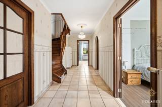 Deze open bebouwing, gebouwd in 1992, is rustig en landelijk gelegen in Sint-Margriete-Houtem en bevindt zich op een royaal perceel van 27a69ca. Met een bewoonbare oppervlakte van 218 m² (volgens EPC) en een EPC-label C biedt deze woning een degelijke constructie met veel ruimte en potentieel.<br /><br />De woning is volledig onderkelderd en beschikt op dit niveau over ruime bergplaatsen en een inpandige garage, wat zorgt voor extra comfort en praktische opbergmogelijkheden.<br /><br />Via de inkomhal op het bel-étageniveau worden de verschillende leefruimtes ontsloten. De woonkamer vormt samen met de eetplaats een aangename en lichtrijke leefruimte. Aansluitend bevindt zich de keuken, die vlot toegang biedt tot de veranda. Deze veranda vormt een volwaardige extra leefruimte en biedt een mooi contact met de tuin en het omliggende groen. Verder bevinden zich op deze verdieping een slaapkamer, een badkamer en een apart toilet, evenals een extra kamer die perfect dienst kan doen als bureau, hobbyruimte of bijkomende slaapkamer.<br /><br />De bovenverdieping omvat vier volwaardige slaapkamers, waardoor deze woning bijzonder geschikt is voor grotere gezinnen of voor wie extra kamers wenst in te richten als bureau, dressing of hobbyruimte. Dankzij de praktische indeling kan elke ruimte functioneel worden benut.<br /><br />Het ruime perceel biedt tal van mogelijkheden voor tuinliefhebbers en wie op zoek is naar rust en privacy, met voldoende afstand tot de buren en een aangename landelijke omgeving.<br /><br />Deze woning combineert een solide bouwstructuur met veel leefruimte, een functionele indeling en een uitstekende ligging in de regio Tienen, ideaal voor wie comfortabel en rustig wil wonen.<br /><br />Interesse?<br />Contacteer Marijke voor een bezoek op 0489/01.14.96 of marijke@polares.eu