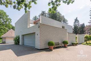 <h3>Exclusieve architectenvilla op toplocatie in villawijk De Lint</h3>
<p>Op een prachtig zuidwestgericht perceel, op wandelafstand van het unieke natuurgebied De Liereman, bevindt zich deze hedendaagse en onder architectuur gebouwde villa. Deze uitzonderlijke woning combineert tijdloze architectuur, royale leefruimtes en een hoogwaardig afwerkingsniveau met een uitstekende bereikbaarheid. Zowel Eindhoven als Antwerpen bevinden zich op slechts ca. 25 minuten rijden, waardoor u geniet van het beste van twee werelden: rust, natuur en een vlotte verbinding.</p>
<p>Bij aankomst wordt u verwelkomd in een ruime inkomhal met vestiaire en gastentoilet. Via stijlvolle dubbele deuren betreedt u de indrukwekkende woonkamer, waar de grote raampartijen een panoramisch zicht bieden op de prachtig aangelegde tuin. Het overvloedige natuurlijke licht en de fraaie tuinzichten creëren een unieke woonbeleving. Aansluitend bevindt zich een open ruimte die perfect dienst kan doen als bureau of leeshoek, open van karakter maar toch afzonderlijk van de leefruimte.</p>
<p>De sfeervolle doorkijkhaard vormt een elegante verbinding tussen de woonkamer en de royale leefkeuken. Deze keuken verkeert in perfecte staat van onderhoud, is uitgerust met kwalitatieve toestellen, beschikt over een groot werkblad en biedt plaats aan een ruime eettafel. Dankzij de grote schuiframen loopt binnen naadloos over in buiten. Achter de keuken bevinden zich een praktische bijkeuken en een aparte wasruimte. De inpandige dubbele garage met automatische poort en personenlift vervolledigt het comfort op het gelijkvloers.</p>
<p>Op de verdieping geeft de royale nachthal toegang tot de indrukwekkende master suite met inloopdressing en een luxueuze badkamer. Daarnaast zijn er nog twee volwaardige slaapkamers met een gedeelde badkamer. De ruime studiekamer kan eenvoudig worden ingericht als vierde slaapkamer en beschikt bovendien over een eigen terras.</p>
<p>Ook buiten weet deze villa te imponeren. De volgroeide, volledig omheinde tuin biedt optimale privacy en vormt een waar groen paradijs. Meerdere zonneterrassen en een overdekt terras nodigen uit om in alle seizoenen van het buitenleven te genieten. Het extra losstaande garagegebouw biedt bijkomende mogelijkheden voor wagenliefhebbers, hobbyruimte of extra opslag.</p>
<p>Naast het uitzonderlijke wooncomfort onderscheidt deze villa zich door haar onderhoudsvriendelijke karakter. Dankzij de duurzame aluminium raamprofielen en de kwalitatieve gevels in gevelsteen zijn er geen schilderwerken aan het buitenschrijnwerk of de buitenmuren nodig, wat resulteert in een stijlvolle uitstraling met een minimum aan onderhoud.<br /><br /><strong>Een uitzonderlijke villa voor wie ruimte, comfort, privacy, kwaliteit en een onderhoudsarme woonomgeving weet te waarderen.</strong></p>
<h3>Troeven van deze woning</h3>
<ul>
<li>Wandelafstand van natuurgebied De Liereman</li>
<li>Zuidwestgericht perceel met optimale bezonning</li>
<li>Personenlift naar de verdieping</li>
<li>Vloerverwarming op gelijkvloers én verdieping</li>
<li>Inpandige dubbele garage met automatische poort</li>
<li>Extra losstaand garagegebouw met bergzolder</li>
<li>Alarmsysteem</li>
<li>Zonnescreens</li>
<li>Fraai aangelegde, volledig omheinde tuin</li>
<li>Grote terrassen en overdekt, verwarmd terras</li>
</ul>