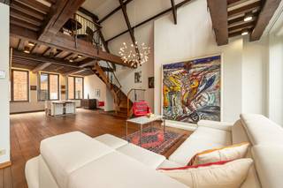 <div>
<div>
<div>
<section>
<div>
<div>
<div>
<div>
<div>
<div>
<p>In het hart van de Antwerpse binnenstad, verschuilt achter een sierlijke renaissance-gevel, schuilt een duplex-appartement dat architecturale grandeur verbindt met de warme leefbaarheid van een authentiek herenhuis.</p>
<p>De leefruimte ontvouwt zich rondom eikenhouten balken en mondt uit in een dubbele verdiepingshoogte die volume biedt. De panoramische ramen met uitzicht op de Antwerpse daken en de naburige boomkruinen laten de ruimte baden in het licht.<br />De separate keuken, met groot raam op de binnenstad, combineert functionaliteit met karakter. <br />Via een houten trap met smeedijzeren balustrade bereikt men de open mezzanine — een brede overloop met bureauruimte of leeshoek. Deze ruimte is tevens gemakkelijk om te vormen tot een extra slaapkamer. Verder beschikt het appartement over twee slaapkamers met eigen badkamer. <br />Een extra troef is de afgesloten garage die te koop is aan 35.000 euro. <br />De combinatie met de locatie in de Braderijstraat — op wandelafstand van de Grote Markt, de Scheldekaaien en gezellige HoReCa — maakt van dit appartement een thuis voor mensen met een liefde voor authenticiteit, kunst en stedelijk leven.</p>
</div>
</div>
</div>
</div>
</div>
</div>
</section>
</div>
</div>
</div>