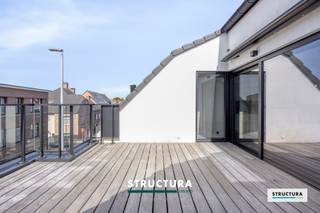 Exclusief penthouse met ruim zonneterras in OpwijkOntdek dit instapklare en energiezuinige penthouse, gelegen in een kleinschalige residentie met slechts 4 woongelegenheden nabij het centrum van Opwijk.Het gebouw dateert van 2020, terwijl het penthouse pas in 2023 voor het eerst in gebruik werd genomen en slechts beperkt werd bewoond. Het appartement is als enige gelegen op de bovenste verdieping en beschikt over een oppervlakte van ca. 107 m2. De grote raampartijen zorgen voor veel lichtinval. Het terras biedt een fijne, rustige plek, die zich uitstekend leent om met wat sfeervol groen extra privacy te creëren.De indeling omvat een aangename leefruimte met volledig uitgeruste kwaliteitskeuken, praktische berging, een ruime slaapkamer en een kleinere kamer die kan dienen als bureel, logeer- of kinderkamer, badkamer met inloopdouche en dubbele lavabo en een apart toilet. Doorheen het appartement zorgen de vele ingemaakte maatkasten voor extra comfort en opbergruimte. Een absolute troef zijn de twee buitenruimtes, waaronder het ruime zonneterras van ca. 22 m2, voorzien van een kwalitatieve luifel en zonwering, alsook een achtergelegen terras van 8m².Verder beschikt het penthouse over elektrische rolluiken en vloerverwarming, en werd er extra aandacht besteed aan de afwerking met vloer- en muurtegels en verlichting. Een lift, geen drempels en een bredere kamerdeur maken het appartement rolstoelvriendelijk. Winkels, scholen en andere voorzieningen bevinden zich op wandelafstand. Een belangrijk financieel pluspunt is dat de verkoop geschiedt onder het stelsel van registratierechten (bv. slechts 2% bij eigen en enige woning) en niet onder het 21% BTW-stelsel.Garagebox en privatieve berging kunnen optioneel worden aangekocht voor €35.000. Tevens mogelijkheid tot aankoop van een tweede garagebox.Een bijzonder verzorgd penthouse voor wie op zoek is naar comfort, privacy en een hoogwaardige afwerking op een centrale locatie in Opwijk.Contacteer Structura voor meer info of een bezoek via info@structura.be of 02/460.80.46