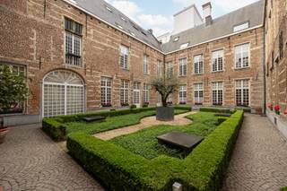 Charmant appartement in historisch 16de eeuws pand met stadstuin.<br />De grote poortdeur geeft toegang tot de gemeenschappelijke stadstuin waarlangs u naar de voordeur van het eigendom loopt. Rustig en privé gelegen in het centrum van de stad. <br />Uitzonderlijke leefruimte met open haard, hoge plafonds en veel lichtinval. De leefkeuken is voorzien van alle gebruikelijke toestellen. Via de leefruimte of de keuken bereikt men een gezellige private binnentuin. <br />De hoofdslaapkamer met ingemaakte kasten en een badkamer voorzien van dubbele wastafel, bad, douche en toilet. De tweede slaapkamer is voorzien ingemaakte kasten en een badkamer met wastafel, bad en toilet.<br />Dit appartement beschikt over een kelder. Een autostaanplaats wordt te koop aangeboden in combinatie met het appartement voor 40.000 euro.