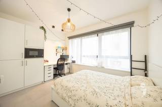<h3><span>Volledig ingerichte studentenkamer</span></h3><p><span>De kamer op het gelijkvloers is meteen klaar om in te trekken en beschikt over een </span><span>ruim bed van 140 cm met handige opberglades</span><span>, een bureau met bureaustoel, kleerkast, nachtkastje, kapstok en boekenplanken. Verduisterende rolgordijnen en moderne verlichting zijn eveneens voorzien.</span></p><p><span>Daarnaast beschikt de kamer over een </span><span>eigen badkamer met douche, lavabo en toilet</span><span>, een koelkast, oven en parlofoon.</span></p><p><span>Ook de gemeenschappelijke ruimtes zijn praktisch ingericht. Studenten kunnen gebruikmaken van een </span><span>moderne keuken met vaatwasser</span><span>, een gezellige relaxruimte, fietsenstalling en aparte ruimte voor afvalsortering. Het gebouw beschikt bovendien over een brandalarminstallatie.</span></p><p><span>Ook energetisch werden de voorbije jaren belangrijke stappen gezet. In 2022 werden extra isolatiewerken uitgevoerd en individuele digitale warmtemeters geplaatst. Daardoor daalde het gasverbruik met maar liefst </span><span>55%</span><span>. Het gebouw heeft momenteel </span><span>EPC-label B</span><span>, waarbij label A binnen bereik ligt.</span></p>