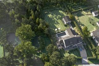 Charmante villa met ruime uitbreidingsmogelijkheden op een uniek privé-domein grenzend aan natuurgebied te Schilde<br /><br />In één van de meest gegeerde en residentiële buurten van Schilde, discreet gelegen aan het einde van een doodlopende straat, bevindt zich deze karaktervolle villa op een perceel van 4968m². Een locatie waar rust, privacy, natuurbeleving en comfort naadloos samenkomen.<br /><br />Indeling gelijkvloers:<br />De villa verwelkomt u via een ruime en lichtrijke inkomhal met vestiaire en gastentoilet. Vanuit hier bereikt u de aangename leefruimte met open haard en grote raampartijen, die zorgen voor een prachtig uitzicht op de fraai aangelegde tuin. Aansluitend bevindt zich een sfeervolle leefveranda, volledig omringd door schuiframen en voorzien van automatische zonnescreens, zodat u het hele jaar door geniet van een maximale lichtinval en een harmonieus zicht op het groen.<br /><br />De volledig uitgeruste keuken biedt eveneens zicht op en directe toegang tot het terras en wordt vergezeld door een praktische berging. Aansluitend bevindt zich een tweede gezellige leef- en eetruimte, voorzien van een houtkachel, wat deze ruimte bijzonder warm en uitnodigend maakt. Tevens is er een aparte bureauruimte, ideaal voor wie praktijk- of kantooractiviteiten aan huis wenst. De inpandige garage met automatische poort biedt plaats aan twee voertuigen.<br /><br />Eerste verdieping:<br />De nachthal leidt naar de master bedroom met ensuite badkamer, aangevuld met drie comfortabele, volwaardige slaapkamers. Daarnaast is er een tweede badkamer met douche en een bijzonder ruime, functionele wasplaats.<br /><br />Tuin en buitenbeleving:<br />De zuidwest-georiënteerde tuin vormt een ware oase van rust, met weidse vergezichten en een bijzonder harmonieuze groenbeleving. De tuin werd smaakvol aangelegd.<br /><br />Bijzonderheden:<br />- Maximale privacy, prestigieuze ligging &amp; ideale zonoriëntatie<br />- Renovaties: 1997 (aanbouw leefruimte) – 1999 (gedeeltelijk buitenschrijnwerk)<br />- Verwarming op aardgas (Viessmann) via radiatoren en convectoren<br />- Dubbele beglazing (hout &amp; aluminium)<br />- Rolluiken aanwezig<br />- Videofonie &amp; automatische toegangspoort<br />- Oprit met plaats voor ca. 6 wagens<br />- Bergzolder toegankelijk via vlizotrap