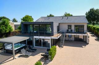 Op een vlot bereikbare ligging nabij Aldeneik vind je deze instapklare villa, ideaal voor wie houdt van modern design en hoog wooncomfort. <br />De woning is doordacht opgebouwd rond volwaardig gelijkvloers wonen, met extra leef- en slaapruimte op tuinniveau.<br /><br />=> Ligging <br />De woning is gelegen dichtbij het mooie en groene Aldeneik, een geliefde buurt nabij het centrum van Maaseik. U woont op wandelafstand van de Maas, omringd door natuur en fietsroutes, met winkels, scholen en horeca vlot bereikbaar.<br /><br />=> Leefniveau op het gelijkvloers<br />- Ruime en lichte leefruimte door de grote raampartijen<br />- Leefkeuken met kwalitatieve afwerking en zicht over de tuin<br />- Bureelruimte/extra slaapkamer aan de voorzijde<br />- Volwaardige masterbedroom met complete dressing en ensuite badkamer<br />- Vloerverwarming, airco en veel natuurlijk licht<br /><br />=> Volwaardig appartement op tuinniveau<br />- Tweede leefruimte met keuken<br />- Twee ruime slaapkamers <br />- Badkamer, wasplaats en bergruimtes<br />- Ideaal voor logees, kinderen, zorg aan huis of hobbyruimte<br /><br />=> Bijgebouw, multifunctioneel te benutten<br />- Ruim bijgebouw met vergaderruimte/eetruimte, toilet en praktische keukenblok<br />- Ruim buitenterras met houten pergola en vrij uitzicht<br />- Perfect voor ontspanning, gasten of professioneel gebruik<br /><br />=> Tuin<br />- Volledig omheind perceel met automatische poort<br />- Verzorgde tuin met open zicht op achterliggende velden<br />- Dubbele carport en fietsenberging<br /><br />=> Waarom dit pand uniek is<br />- Gelijkvloers wonen gecombineerd met volwaardige extra woonentiteit<br />- Energiezuinig met zonnepanelen<br />- Geschikt voor verschillende levensfases<br /><br />=> Indeling<br />- Gelijkvloers: inkomhal, apart toilet, woonkamer, leefkeuken, bureelruimte/extra slaapkamer, ouderlijke slaapkamer, dressing, badkamer <br />- Tuinniveau- tweede woongedeelte: woonkamer, keuken, twee slaapkamers, badkamer, apart toilet, tuinkamer, wasplaats, berging met vaste kastenwand, technische ruimte en extra berging;<br />- Bijgebouw met terras<br />- Dubbele carport <br />- Fietsenberging<br />- Zolder: te bereiken via vaste trap