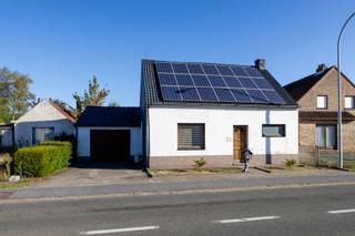 <p>Deze charmante woning, oorspronkelijk gebouwd in <strong>1930</strong>, werd in <strong>2022 gedeeltelijk gerenoveerd</strong> en combineert karakter met hedendaags wooncomfort. Dankzij onder meer de vernieuwde leidingen, conforme elektriciteit, zonnepanelen en een EPC-label C is dit een interessante woning voor wie op zoek is naar ruimte, gezelligheid en praktische troeven.</p>
<p>Bij het binnenkomen kom je terecht in de <strong>lichtrijke leefruimte</strong>, die tijdens de renovatie werd opengetrokken door het verwijderen van een muur. Hierdoor ontstond een aangenamere, ruimere woonbeleving met een vlotte verbinding naar de ingerichte eetkeuken. De keuken is uitgerust met onder meer een <strong>koelkast, inductiekookplaat en vaatwasser</strong>. Vanuit de keuken bevindt zich ook de trap naar de bovenverdieping.</p>
<p>Achter de keuken loopt de woning verder door naar de <strong>gezellige veranda</strong>, waar een <strong>pelletkachel</strong> zorgt voor extra warmte en sfeer. Daarnaast is er ook nog een <strong>houtkachel</strong>, wat bijdraagt aan het warme en huiselijke karakter van de woning.</p>
<p>Op het gelijkvloers bevindt zich de <strong>volledig vernieuwde badkamer</strong>, voorzien van een <strong>douche, dubbele lavabo en toilet</strong>. Verder is er een <strong>zeer ruime inpandige garage</strong>, waar niet alleen plaats is voor een wagen, maar ook voor extra bergruimte, fietsen en de aansluiting voor wasmachine en droogkast.</p>
<p>Op de bovenverdieping bevinden zich <strong>3 slaapkamers</strong>, ideaal voor een gezin, thuiswerkruimte of hobbykamer.</p>
<p>De woning is gelegen op een mooi perceel van <strong>873 m²</strong>. De tuin is <strong>volledig omheind</strong>, wat zorgt voor privacy en veiligheid, ideaal voor kinderen of huisdieren.</p>
<p>Ook op energetisch vlak beschikt deze woning over verschillende belangrijke troeven. Zo liggen er <strong>22 zonnepanelen</strong>, is het <strong>dak geïsoleerd</strong> en is er <strong>airco aanwezig in de leefruimte en keuken</strong>, die zowel voor verkoeling als verwarming kan zorgen. De woning wordt verwarmd via een combinatie van <strong>elektrische verwarming, airco en kachels</strong>. De elektrische installatie is bovendien <strong>conform gekeurd</strong>. Het EPC bedraagt <strong>242 kWh/m² per jaar</strong>, goed voor <strong>label C</strong>.</p>
<p>Kortom: een gezellige en ruime woning met karakter, een mooi perceel, conforme elektriciteit, zonnepanelen en heel wat renovaties die reeds werden uitgevoerd.</p>