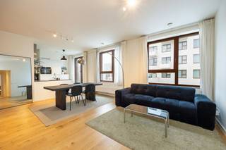 Zonnig en comfortabel appartement gelegen op het Eilandje. <br />Entree met gastentoilet leidt naar een ruime woonkamer. De open keuken voorzien van alle gebruikelijke toestellen geeft rechtstreeks toegang tot een Zuid-West georiënteerd terras. <br />Vervolgens beschikt het appartement over een eerste slaapkamer dewelke tevens kan gebruikt worden als thuiswerkkantoor of dressing. De hoofdslaapkamer heeft aanpalend een eigen badkamer voorzien van wastafel en bad. Een tweede badkamer is uitgerust met een douche. <br />Bijkomend is er een staanplaats te koop aan 35.000 euro.