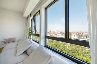 Op een boogscheut van de Nationale Bank, het Stadspark en het bruisende 't Zuid, vinden we dit recent gerenoveerde appartement terug op de 7e verdieping met een uniek zicht over de stad. <br /><br />Het appartement is ook ideaal voor het uitbaten van een airbnb. <br /><br />We betreden het appartement via de open gang met links de open en volledig geïnstalleerde keuken met aangrenzend de leef -en eetruimte. Hier genieten we van een zalige lichtinval dankzij de vele raampartijen. De keuken is voorzien van een ijskast met vriezer, een combi oven, vaatwasser en een elektrische kookplaat met dampkap. <br /><br />Aan de andere kant vinden we nog 3 slaapkamers en 2 badkamers terug. De eerste badkamer is voorzien van een inloopdouche en een dubbele wastafel. Alsook vinden we hier de aansluitingen terug voor de wasmachine. De tweede badkamer is voorzien van een douche in bad, een toilet en ook een dubbele wastafel. <br /><br />Daarnaast beschikt het appartement nog over een apart toilet en een privatieve kelderberging. <br /><br />Het volledige appartement is voorzien van een authentieke blokjesparket, dewelke volledig opnieuw werd behandeld en hersteld.  <br /><br />Als extra troef beschikt het appartement nog over de exclusieve dakrechten. Voor een deel loopt er nog een huurcontract op dat gerespecteerd moet worden. 