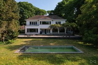 <p>Tussen de glooiende velden van Boutersem, op een domein van maar liefst <strong>5,5 hectare</strong>, ligt een woning die zelden op de markt komt, en nog zeldzamer is in karakter: <strong>Huize Balder</strong>. Deze exclusieve villa combineert een rijke geschiedenis met een unieke architectuur en uitzonderlijke privacy. Het is een plek waar verleden en toekomst elkaar ontmoeten in een oase van rust, stijl en mogelijkheden.<br /><br /><strong>Huize Balder werd gebouwd in het interbellum door Alphonse Cappuyns</strong>, een briljante chemicus en pionier in de industriële productie van citroenzuur. Als oprichter van La Citrique Belge werkte Cappuyns nauw samen met Italiaanse partners – een band die zijn weerslag vond in de bouw van deze villa. <strong>Italiaanse (Siciliaanse) elementen zoals zuilengalerijen, arcades en mediterrane terrassen</strong> werden harmonieus geïntegreerd in een verder klassiek Belgische woningstijl. Het resultaat is een architecturaal geheel dat warmte, verfijning en wereldse allure uitstraalt.<br /><br />Met een <strong>bewoonbare oppervlakte van ca. 976 m²</strong> biedt de villa ruimte in overvloed. Er zijn <strong>10 slaapkamers</strong>, meerdere badkamers, een monumentale traphal met authentieke details en lichte leefruimtes met zicht op het parkdomein. Buiten vindt u een <strong>verwarmd zwembad</strong>, <strong>drie tennisvelden</strong> en meerdere terrassen die uitkijken op het omliggende groen. Alles is omgeven door een <strong>volledig afgeschermd domein</strong>, bereikbaar via een private oprijlaan, waardoor <strong>absolute privacy gegarandeerd is</strong>.<br /><br /><span>Ook qua ligging scoort deze eigendom uitzonderlijk goed.</span><span> Een </span><strong>strategische uitvalsbasis tussen Leuven en Tienen</strong><span>, met </span><strong>uitstekende verbindingen naar Brussel via de E40</strong><span><strong>.</strong> <br /><br /></span>Deze uitzonderlijke eigendom biedt <strong>veel meer dan alleen woonruimte</strong>. Dankzij haar schaal en indeling is Huize Balder perfect geschikt voor wie een <strong>familiedomein, praktijkruimte, retreatlocatie of zelfs een kleinschalige hospitality-ontwikkeling</strong> voor ogen heeft. Denk aan een exclusieve B&B, kunstenaarsresidentie, of een inspirerende thuis voor wie wonen en werken wil combineren. De mogelijkheden zijn legio, en de structuur van het pand leent zich uitstekend tot verdere verfijning.<br /><br />Maar Huize Balder is vooral ook een plek met een ziel. <strong>Een woning met een naam, een verhaal en een verleden.</strong> In de vorige eeuw fungeerde het domein als ontspanningsoord voor sportieve en culturele weekends. Kinderen speelden in de bossen, volwassenen genoten van rust, fitness en gezamenlijke diners op de terrassen. Vandaag is het tijd voor een nieuw hoofdstuk – geschreven door wie nu op zoek is naar iets écht bijzonders.<br /><br />Neem contact met ons op voor een bezoek of meer informatie. We laten u graag kennismaken met een plek die u nooit meer vergeet.<br /><br />AANDELENOVERDRACHT MOGELIJK!</p>