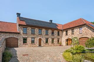Ruim karakteristiek huis met 4 slaapkamers, een grote tuin en authentieke charme. Dit uitzonderlijke pand combineert de charme van een authentieke kleine boerderij met het comfort van een recente uitbreiding uit 2013. Met een woonoppervlakte van maar liefst 522 m² (te verifiëren aan de hand van het PEP), een perceel van 1 726 m² en een veelzijdige indeling is dit huis ideaal voor grote gezinnen, zelfstandigen of mensen die op zoek zijn naar een unieke woonervaring met veel ruimte.Indeling: entreehal, kantoor, apart gastentoilet, een grote, lichte woonkamer, een kantoor met mezzanine, bijkeuken/wasruimte, badkamer, keuken en een tweede gezellige woonkamer. Dankzij de praktische indeling is het bovendien mogelijk om op de begane grond een slaapkamer in te richten.Op de eerste verdieping bevinden zich vier ruime slaapkamers, een tweede badkamer, een wellnessruimte met infraroodsauna, een inloopkast, een terras grenzend aan de ouderslaapkamer en een bibliotheek/kantoor. Daarnaast beschikt het huis over een ruime en volledig geïsoleerde zolder, ideaal als extra opslagruimte.Buiten kunt u genieten van een prachtige tuin met verschillende terrassen en een eigen boomgaard met onder andere vijgen-, appel-, kersen-, perzik- en pruimenbomen. Het huis beschikt tevens over een garage en een ruime parkeerplaats die plaats biedt aan meerdere auto’s.Het oorspronkelijke linkergedeelte van het huis heeft zijn authentieke karakter behouden, terwijl het rechtergedeelte in 2013 volledig is herbouwd en zowel op de begane grond als op de eerste verdieping is voorzien van vloerverwarming op aardgas. De hoofdslaapkamer en de bibliotheek zijn voorzien van airconditioning.Het huis straalt veel karakter uit dankzij de hoogwaardige en unieke afwerking, met onder meer prachtige binnendeuren vervaardigd uit deuren afkomstig van Indiase tempels en een gevarieerde keuze aan materialen zoals travertijn in de inkomhal, parket, leisteen in het kantoor, blauwe hardsteen aan de buitenkant en karaktervolle kasteeltegels in de tweede zitkamer. Bovendien zorgen de geïnstalleerde zonnepanelen voor een meerwaarde op het vlak van energie-efficiëntie. Te koop via Immo Beguin, uw vastgoedexpert sinds 2009.Meer informatie of een bezichtiging? Neem contact op met emmy@immobeguin.be