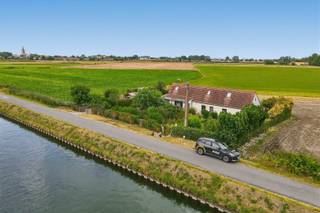 Ontdek deze uitzonderlijke vrijstaande woning op een prachtig perceel van ca. 984 m², idyllisch gelegen langs het kanaal Nieuwpoort-Plassendale op slechts enkele kilometers van Middelkerke en Oostende. Dankzij de royale tuin rondom de woning geniet u hier van een uniek en vrij uitzicht over het water en de uitgestrekte achterliggende velden tot in Middelkerke. Een locatie waar rust, ruimte en natuur perfect samenkomen.<br /><br />Bij het betreden van de woning wordt u verwelkomd in een ruime en stijlvolle inkomhal met apart gastentoilet. De open vide creëert meteen een aangenaam gevoel van ruimte en licht. De lichtrijke leefruimte, met gezellige zit- en eethoek, vormt het hart van de woning en sluit naadloos aan op de volledig ingerichte open keuken, voorzien van alle nodige toestellen met aanpalende koele bergruimte.<br />Daarnaast beschikt de woning over een sfeervol leeshoekje met een prachtig uitzicht op het hinterland, een praktische en ruime wasberging met extra douche, een polyvalente kamer die momenteel is ingericht met een Finse sauna en een handige kelderberging.<br /><br />Op de eerste verdieping bevinden zich een ruime overloop, twee gezellige slaapkamers en een verzorgde badkamer uitgerust met een ligbad, lavabo en toilet.<br /><br />Ook buiten heeft deze eigendom heel wat te bieden. U beschikt er over twee afzonderlijke tuinbergingen, een vrijstaande garage met elektrische sectionaalpoort en een aansluitende fietsenberging. De ruime tuin biedt bovendien tal van mogelijkheden om optimaal te genieten van de unieke ligging en de rustige omgeving.<br />Bent u op zoek naar een instapklare woning met karakter, een uitzonderlijke ligging en een adembenemend uitzicht? Dan is deze eigendom absoluut een bezoek waard.<br />Vraag vandaag nog uw bezoek aan voor onze kijkdag op zaterdag 22 augustus tussen 14.00 u en 16.00 u, uitsluitend op afspraak.<br /><br />Richtprijs: De vermelde prijs betreft een richtprijs. Elk bod, zowel hoger als lager dan deze richtprijs, wordt voorgelegd aan de eigenaars, die vrij zijn om dit al dan niet te aanvaarden.<br /><br />EPC: 240 kWh/m² - UC: 6898463 - Gvg Lwag Gvkr Gvv Gmr - Ref. MI25003