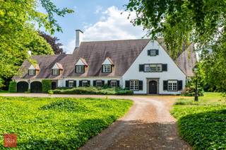 Villa gelegen op perceel van +/- 9.600m², bestaande uit inkomhal, bureel, living, eetplaats, keuken, bijkeuken (wasplaats), dagelijkse woonkamer (tv-kamer), dubbele garage, 5 slaapkamers, 3 badkamers, dressing, ruime zolder met vaste trap, kelders, terrassen, berging en zuidgerichte tuin. Mogelijkheid +/- 2ha landbouwgrond bij te kopen.<br /> 