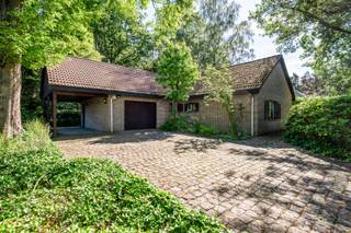 Welkom in deze vrijstaande woning, gelegen aan de gegeerde Bethaniënlei in Sint-Job-in-'t-Goor. Hier woont u in een residentiële en groene omgeving, gekenmerkt door ruime percelen, volwassen bomen en een aangenaam buurtgevoel. Dankzij de centrale ligging bevinden winkels, scholen, openbaar vervoer en het centrum van Brecht zich op korte afstand.<br />Voor liefhebbers van natuur en ontspanning is dit een absolute toplocatie. De woning grenst aan uitgestrekte bosgebieden en bevindt zich vlakbij het Antitankkanaal, het Albertkanaal en de prestigieuze Rinkven International Golf Club. Tal van wandel- en fietsroutes starten letterlijk in de buurt van de woning.<br /><br />Indeling van de woning:<br />Via de inkomhal met vestiairekasten en gastentoilet komt u in de bijzonder ruime leefruimte van ca. 70 m². De leefruimte bestaat uit een salon en eetkamer en geniet dankzij de grote raampartijen van een mooie connectie met de tuin. Via de veranda heeft u rechtstreeks toegang tot het terras en het groen.<br />De gesloten keuken beschikt over een praktische bijkeuken met aansluitingen voor wasmachine en droogkast. Vanuit de bijkeuken bereikt u de ruime garage.<br />Verder bevinden zich op het gelijkvloers twee ruime slaapkamers en een badkamer uitgerust met ligbad en douche. Via een uitklapbare trap in de garage is er toegang tot de zolderruimte.<br /><br />Buitenruimte & parkeren:<br />De bosrijke tuin vormt zonder twijfel één van de grootste troeven van deze eigendom. Het perceel biedt veel privacy en is aangelegd met een grote diversiteit aan bomen, struiken en beplanting. Daarnaast beschikt de tuin over een vijver, zonneterras, veranda en een praktische tuinberging. Een oase van rust en groen.<br />De woning beschikt over een ruime garage met automatische poort, een carport en een oprit voor meerdere wagens.<br /><br />Troeven van de woning:<br />- Rustige en groene topligging in Sint-Job-in-'t-Goor<br />- Ruim perceel met veel privacy<br />- Grote leefruimte van ca. 70 m²<br />- Gelijkvloers wonen mogelijk<br />- Garage, carport en ruime oprit<br />- Bosrijke tuin met vijver en veranda<br />- Uitbreidingsmogelijkheden (onder voorbehoud van vergunning)<br />- Vlakbij Rinkven Golf Club en natuurgebieden<br /><br />Kortom:<br />Deze woning is ideaal voor wie op zoek is naar rust, ruimte en groen, zonder in te boeten op bereikbaarheid. Dankzij de gelijkvloerse indeling, het ruime perceel en de uitbreidingsmogelijkheden biedt deze eigendom een uitstekende basis om een droomwoning te creëren op een toplocatie in Sint-Job-in-'t-Goor. <br /><br />Absoluut een bezoek waard!