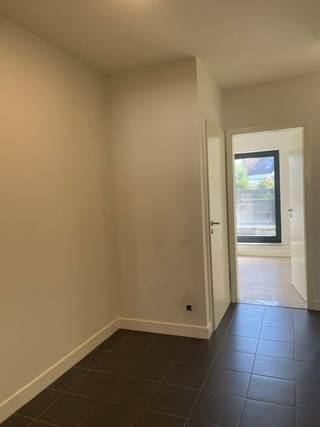 Het appartement omvat volgende ruimtes: Inkomhal, afzonderlijk toilet, ruime woonkamer met open ingerichte keuken, berging, 3 slaapkamers, ingerichte badkamer, ruim terras achteraan, garage nr. 16, en elektrische verwarming.
