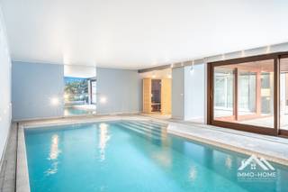 Deze zeer riante woning, 455 m2 bewoonbaar (co-housing?), ontvangt je in een ruime inkomhal (met gastentoilet). Via een wandhoge pivoterende deur kom je zo verder tot in de bijzonder ruime leefruimte met open keuken. Net zoals in de rest van het pand is er voorzien in vloerverwarming- én koeling, waardoor nergens storende elementen aanwezig zijn. In de zithoek is er een grote inbouwhaard aanwezig, en in een hoekje vinden we een mooi verborgen bureel terug. De keuken is voorzien van alle moderne kookcomfort van hoge standaards, en op en aan het dubbele kookeiland is het heerlijk kokerellen voor gasten en familie. Een gekoelde berging maakt hier het plaatje compleet. Op de eerste verdieping is er voorzien in twee heel ruime slaapkamers met een gemeenschappelijk overdekt terras, en met middenin een eerste badkamer met zowel ligbad als inloopdouche (plus een tweede toilet). Op dit niveau vinden we ook een fitness-ruimte terug, met zicht op een eigen overdekt balkon. De bovenste verdieping wordt volledig ingenomen door de master bedroom, met een aanpalende riante badkamer (met een derde toilet) en een grote dressing. Ook hier is er een groot terras aanwezig. De mooiste troef vinden we achteraan het pand : daar is een binnenzwembad voorzien, inclusief sauna en douche. Deze ruimte wordt bereikt via een tussenplaats (ook rechtstreeks bereikbaar vanuit de fitness), waar voorzien is in een bijkeuken en een omkleedruimte (met eigen toilet). In het midden van dit alles ligt een groot buitenterras, waar je geniet van voldoende privacy. Net naast de woning is er parkeerplaats voor meerdere wagens. Inschrijven via mail voor de bezoekdag op donderdag 03/09 naar stefan@immo-home.be.