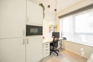 <h3><span>Volledig ingerichte studentenkamer</span></h3><p><span>De kamer op het gelijkvloers is meteen klaar om in te trekken en beschikt over een </span><span>ruim bed van 140 cm met handige opberglades</span><span>, een bureau met bureaustoel, kleerkast, nachtkastje, kapstok en boekenplanken. Verduisterende rolgordijnen en moderne verlichting zijn eveneens voorzien.</span></p><p><span>Daarnaast beschikt de kamer over een </span><span>eigen badkamer met douche, lavabo en toilet</span><span>, een koelkast, oven en parlofoon.</span></p><p><span>Ook de gemeenschappelijke ruimtes zijn praktisch ingericht. Studenten kunnen gebruikmaken van een </span><span>moderne keuken met vaatwasser</span><span>, een gezellige relaxruimte, fietsenstalling en aparte ruimte voor afvalsortering. Het gebouw beschikt bovendien over een brandalarminstallatie.</span></p><p><span>Ook energetisch werden de voorbije jaren belangrijke stappen gezet. In 2022 werden extra isolatiewerken uitgevoerd en individuele digitale warmtemeters geplaatst. Daardoor daalde het gasverbruik met maar liefst </span><span>55%</span><span>. Het gebouw heeft momenteel </span><span>EPC-label B</span><span>, waarbij label A binnen bereik ligt.</span></p>