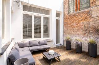 In een charmant en authentiek gebouw bevindt zich dit appartement met terras op de gelijkvloerse verdieping. Gelegen in de Minderbroedersrui bevindt u zich in het hart van het historische centrum van Antwerpen, op wandelafstand van de Grote Markt, de Kathedraal van Onze-Lieve-Vrouw en tal van winkels, restaurants en gezellige cafés. Deze locatie combineert een vlotte bereikbaarheid met een unieke mix van levendige stadsdynamiek en historische charme.<br /><br />Bij het betreden van het appartement komt u terecht in de lichtrijke leefruimte, die naadloos overgaat in de open keuken, uitgerust met kwalitatieve inbouwtoestellen. Vanuit deze ruimte heeft u bovendien rechtstreeks toegang tot het gezellige terras, waar u in alle rust kan genieten van een aangenaam buitenmoment.<br /><br />Aan de achterzijde van het appartement bevindt zich een ruime slaapkamer, voorzien van praktische inbouwkasten. Aansluitend vindt u de badkamer, uitgerust met een royale inloopdouche en een dubbele wastafel met voldoende opbergruimte. Aan de voorzijde bevindt zich een tweede kamer, momenteel ingericht als bureauruimte, die zich dankzij haar flexibiliteit perfect leent als kinder- of logeerkamer.<br /><br />Kortom, een charmant en instapklaar appartement met terras op een toplocatie, ideaal voor wie comfortabel wil wonen in het hart van de stad.<br /><br />Interesse? Contacteer LISTED voor een bezoek: +32 3 283 51 51.