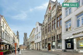 Achter de karaktervolle gevel van dit bijzonder pand in de Vlamingstraat, op een steenworp van de Grote Markt en het Belfort, schuilt een verrassende royale oppervlakte.<br />Met maar liefst ongeveer 260m² commerciële ruimte op het gelijkvloers en ongeveer 500m² bruikbare residentiële ruimte op de bovenverdiepingen biedt dit vastgoed een zeldzame waaier aan ontwikkelings- en investeringsmogelijkheden.<br /><br />Indeling:<br />- Gelijkvloers: handelsgelijkvloers (260m²) leegstaand (momenteel in gebruik als opslagruimte) - verschillende lokale en bergingen (keuken, badkamer, toilet..), terras<br />- Kelder (220m²) is onderverdeeld in verschillende ruimtes.<br />- Tussenverdieping : Opslagruimte vooraan (54m²)<br />- Eerste verdieping (185m²) : Woonst bestaande uit voorhuis ingedeeld in overloop, badkamer, woonkamer ingedeeld in eet- en zithoek, keuken.<br />Achterhuis ingedeeld in nachthal, 5 slaapkamers, dakterras<br />- Tweede verdieping (185m²): Voorhuis ingedeeld in 3 kamers, achterhuis ingedeeld in nachthal, toilet en 4 slaapkamers.<br />- 3 zolders (125m²) met vaste trap<br /><br />Mogelijkheid om dubbele garage aan te kopen.<br /><br />Investeringspotentieel & Troeven<br />Dankzij het indrukwekkende bouwvolume en de flexibele indeling leent deze eigendom zich perfect voor diverse invullingen. De unieke symbiose van een ruim handelsgelijkvloers en een royaal woonvolume maakt het pand uiterst aantrekkelijk voor:<br /><br />Ondernemers & vrije Beroepen: Combineer uw winkel, showroom, kantoor of praktijk op de begane grond met zeer ruim comfortabel wonen op de verdiepingen.<br /><br />Investeerders & ontwikkelaars: Strategisch gelegen opbrengsteigendom met potentieel voor herontwikkeling of meerwoonstproject (mits het bekomen van de nodige vergunningen).<br /><br />De eigendom wordt aangeboden via de Pre-sale formule. Van 16/10/2026 om 09:00 tot 04/12/2026 om 16:00 kan u het handelspand op afspraak komen bezichtigen en een bod uitbrengen. De vermelde prijs is een instelprijs. Voor meer info, gelieve contact op te nemen met de dossierverantwoordelijke.<br /><br />Bestuursmaatregelen in het maatregelenregister: nee