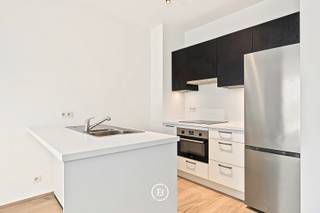 Op een rustige locatie, vlak bij de Avenue Paul Hymans, bevindt zich dit prachtige appartement in een recent gebouw op de eerste verdieping. Met een bewoonbare oppervlakte van 63 m² en een terras biedt deze woning een aangename woonomgeving waar comfort en kwaliteit centraal staan.<br /><br />Bij het binnenkomen komt u terecht in de inkomhal met gastentoilet en een praktische wasruimte. De volledig uitgeruste open keuken sluit naadloos aan op de ruime leefruimte, die dankzij de grote raampartijen geniet van een overvloed aan natuurlijk licht. Vanuit de woonkamer heeft u rechtstreeks toegang tot het terras.<br /><br />Het appartement beschikt over een slaapkamer (14 m²) en een badkamer met douche. Een private kelderberging vervolledigt het geheel. Daarnaast is er een gemeenschappelijke fietsenberging aanwezig en mogelijkheid tot het huren van een parkeerplaats.<br /><br />Deze woning onderscheidt zich door haar hoogwaardige afwerking en moderne uitrusting. Zo zijn onder meer dubbele beglazing, een versterkte veiligheidsdeur, een intercom, een ventilatiesysteem met dubbele luchtstroom, een waterontharder, ingebouwde kasten, gordijnen en verlichtingsarmaturen aanwezig.<br /><br />Dankzij de uitstekende ligging, de kwaliteitsvolle afwerking en de aantrekkelijke buitenruimte is dit een appartement dat onmiddellijk weet te bekoren.<br /><br />Gemeenschappelijke kosten: € 115/maand<br />Voorschot water en verzekering: € 150/maand