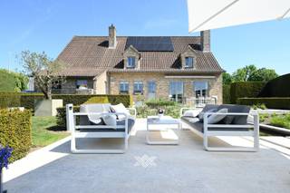 Deze karaktervolle villa is gelegen op een perceel van 951 m² en werd opgetrokken in 1986, met oog voor kwaliteit en duurzaamheid. In de loop der jaren werden bovendien diverse opfrissingswerken uitgevoerd, waaronder de installatie van een nieuwe keuken, een aircosysteem, een zonneluifel en de plaatsing van tien zonnepanelen. De ruime inkomhal met gastentoilet geeft toegang tot de lichtrijke woon- en eetkamer, die dankzij de grote raampartijen uitkijkt op het omliggende groen en de fraai aangelegde tuin. Aansluitend bevindt zich de volledig uitgeruste keuken, voorzien van kwalitatieve inbouwtoestellen van het merk Miele. Vanuit de keuken bereikt u een koele berging en de dubbele inpandige garage. Op het gelijkvloers bevindt zich eveneens een royale bureauruimte aan de voorzijde van de woning. De eerste verdieping omvat vier volwaardige slaapkamers, een dressing/berging en een ruime badkamer uitgerust met een ligbad, een inloopdouche, een toilet en een dubbele wastafel. De zolderverdieping is bereikbaar via een uitschuifbare trap vanuit één van de slaapkamers en biedt extra opbergruimte. De tuin is volledig volgroeid en biedt voldoende rust en privacy. Dankzij de zuidwestelijke oriëntatie kunt u hier volop genieten van de zon.<br /><br />Ook de ligging is hier een bijzonder grote troef gezien de ringweg slechts op 500 meter afstand ligt met de oprit naar de A17. <br /> <br />Benieuw? guillian@landbergh.be of 09 278 78 79.