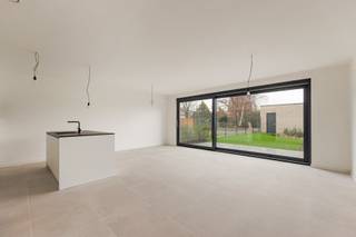 Dit recent opgeleverde appartement heeft een praktische indeling. Via de ruime inkomhal met gastentoilet kom je terecht in de lichte en riante leefruimte met open keuken. De moderne keuken is afgewerkt met een natuurstenen werkblad en volledig uitgerust met kwalitatieve toestellen, waaronder een inductiekookplaat, dampkap, oven, vaatwasmachine en ingebouwde koelkast. Vanuit de woonkamer heb je directe toegang tot de zonnige, mooi aangelegde tuin met terras. Achteraan de tuin bevindt zich een ruime garage van maar liefst 35m², afzonderlijk aan te kopen voor 35.000 euro (excl. kosten), alle voorzieningen voor een laadpaal zijn reeds voorzien. Het appartement beschikt verder over twee ruime slaapkamers, een extra dressing en een stijlvolle badkamer met dubbele lavabo en inloopdouche. Daarnaast is er een handige berging met aansluiting voor een wasmachine. Bovendien voldoet het appartement aan alle hedendaagse energienormen en is het voorzien van vloerverwarming, een warmtepomp, zonnepanelen, ventilatiesysteem C en regenwaterrecuperatie voor de toiletten en mogelijk ook de wasmachine. Zo geniet u van een energiezuinig en comfortabel woonklimaat. Extra troef: het verwachte E-peil bedraagt minder dan E20, wat recht geeft op een korting van 50% op de onroerende voorheffing gedurende 5 jaar. AANKOOP MOGELIJK AAN 6% BTW! Contacteer ons voor meer info op 03 568 03 03 of lauren@vastgoed03.be 