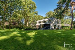 Instapklare high-end villa in meer- en golfomgeving.<br /><br />Deze modernistische woning met unieke invulling biedt alle comfort en rust in een oase van groen en bos.<br /><br />Bij het betreden van dit pand worden we meteen verbaasd door de dakramen naast de woonkamer en de aandacht voor bijzondere, exclusieve materialen. De leefruimte is voorzien van een mooie gashaard en wordt door een kastenwand gescheiden van de bureau-ruimte. Aansluitend is er een eetplaats met geweldige wijnkast, alsook een volledig uitgeruste keuken met speciale kookapparatuur.<br /><br />Naadloos weggewerkt in de keukenwand vinden we een deur die toegang biedt tot de gelijkvloerse slaapkamer met eigen badkamer, de berging en wasplaats met koelcel en gelijkvloerse staanplaats voor de wagen.<br />De woning biedt alle moderne comfort en werd uitgerust met de nieuwste technieken waaronder alle voorbereidingen om een lift te kunnen installeren. Door de gebruikte technieken is de woning natuurlijk ook energiezuinig. (E50)<br /><br />Op de eerste verdieping vinden we een ruime master-bedroom met eigen haard die 180° zicht biedt over de aangelegde tuin. Hierbij werd zowel een bad als douche voorzien met op het dakterras tevens een stoomcabine en whirlpool. Naast de badkamer vinden we een inloopdressing met indirecte verlichting en lichtkoepel voor overdag.<br /><br />Behalve het bijzondere leefconcept met rijkelijke lichtinval overal op de bovengrondse verdiepingen, heeft de woning nog een ruime kelder dewelke langs binnen en met een autolift langs buiten toegankelijk is. Deze ruimte van 350 m2 kan aangewend worden tot een enorm atelier of een bijzondere stalplaats voor een prachtige autocollectie. Andere invullingen zijn natuurlijk ook mogelijk gezien er natuurlijk licht binnenvalt en er ook op de ondergrondse verdieping ramen voorzien zijn.<br /><br />Bekijk ook zeker onze website voor de interactieve grondplannen.<br />Meer info via Jean.Heylen@imovastgoed.be of via 015/34.34.54.