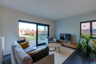 In een recent gebouwde residentie vinden we dit prachtige gelijkvloers appartement met ruime tuin terug. <br />We komen binnen via een gezellige gang en vinden hier meteen de twee spatieuze slaapkamers. De badkamer beschikt over een grote inloopdouche en een wastafel met spiegelkast. De leefruimte baadt in het zonlicht dankzij de grote raampartijen die op de tuin uitgeven. De open keuken met kookeiland is volledig uitgerust met alle toestellen en geniet van voldoende opbergkasten.<br />Aan de achterzijde van het appartement vinden we een gezellig terug terug en een prachtige tuin. Een praktisch tuinhuis en twee staanplaatsen maken het plaatje compleet.<br />Gemeenschappelijke kosten + 50 euro/per maand