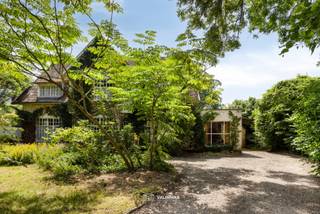 VALIMMAS verkoopt deze riante (± 600m² bebouwd !) en uniek gelegen doktersvilla met praktijkruimte, garage en een grote zuidgeoriënteerde tuin van ± 16 are 71 (eventueel nog uit te breiden tot ± 28 are),...
Deze zeer ruime en solide villa omvat op het gelijkvloers een centrale inkomhal, een toilet, een berging, een bureel, een keuken, een salon en een living met imposante schouw/open haard en uitzicht op het zonneterras en de beboste tuin. De praktijkruimte (voormalige dokterspraktijk) beschikt ook over een aparte toegang met hal en toilet, een wachtkamer of bureel, en de praktijkruimte of bureel met zicht op de tuin. Er is tevens een ruime garage beschikbaar.
De verdieping herbergt een centrale overloop, zes slaapkamers waarvan 1 met dressing, en een badkamer.
De zolderruimte is bereikbaar via een vaste trap, en kan desgewenst nog verder ingericht worden.
Het grootste deel van de woning (± 100m²) is eveneens onderkelderd, met oa. een wijnkelder, de stookplaats, proviandkelders,...
Een deel van de actuele tuin grenst aan de achtergelegen Langevijver(straat), en werd reeds verkaveld in 2 bouwgronden voor open bebouwing (532m² en 570m² , en elk circa 14,60m breed en gemiddeld 38m diep). OPTIONEEL: ook mogelijkheid tot aankoop van het geheel (zijnde de villa op 16a71 + de 2 bouwgronden = ± 27a73) mits de vraagprijs van € 1.299.000.
Deze residentieel gelegen majestueuze villa met grote raampartijen wacht op een zorgvuldige renovatie om opnieuw te schitteren als de parel van weleer.