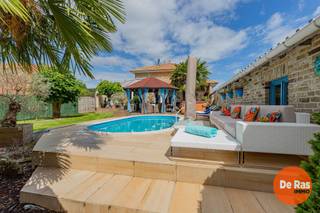 BEZOEKDAG ZATERDAG 1 AUGUSTUS VANAF 10U (ENKEL OP AFSPRAAK!!)<br />SINT-LIEVENS-HOUTEM - Spaanse villa met zwembad <br /><br />Droomt u van een woning met een permanente vakantiesfeer? Dan zal deze unieke villa in Sint-Lievens-Houtem u meteen weten te bekoren. Gelegen op een ruim perceel van maar liefst 2.151 m² combineert deze eigendom royale leefruimtes, hedendaags comfort en een prachtig aangelegde tuin met zwembad.<br /><br />De woning beschikt over een ruime bewoonbare oppervlakte van circa 250m² en biedt een bijzonder praktische indeling. Via de inkomhal bereik je zowel toilet, garage als de leefkamer. <br />De keuken is volledig ingericht en heeft een bijkomende keukenberging/wasplaats. <br /><br />Buiten waant u zich in een zuiders vakantieoord. De tropisch aangelegde tuin vormt samen met de gezellige patio, het zwembad, de pergola en de jacuzzi een unieke plek om te ontspannen en te genieten met familie en vrienden. <br />De parktuin met bijgebouwen maakt dit tot een compleet aanbod. <br /><br />Ook op vlak van energie en technologie scoort deze woning goed dankzij de aanwezigheid van zonnepanelen, een thuisbatterij en een laadpaal voor elektrische voertuigen.<br /><br />Troeven:<br />- 3 slaapkamers en 2 badkamers<br />- Vernieuwde badkamer op het gelijkvloers<br />- Ruime inpandige garage<br />- Deels onderkelderd en voorzien van kruipkelder<br />- Tropische tuin met patio, zwembad, jacuzzi en pergola<br />- Bijgebouw van 46 m² als buitengarage, opberg en technieken. <br />- Unieke zuiderse architectuur met uitgesproken karakter<br /><br />Voor meer informatie of een bezoek, kan u ons steeds contacteren: 053/60.65.60.