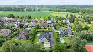 Deze exclusieve, vrijstaande villa in landelijke stijl in Wemmel straalt pure klasse uit. Met een royale bewoonbare oppervlakte van 526 m² en een superieure afwerkingsgraad geniet u hier van uitzonderlijk wooncomfort. De zandkleurige gevel combineert harmonieus met charmante dakkapellen en een monumentale glaspartij bij de inkom. De woning is energie-efficiënt uitgerust met zonnepanelen en een hoogwaardig alarmsysteem.De villa ligt op een discreet perceel, volledig aan het oog onttrokken via een lange privé-inrit. Dit garandeert honderd procent privacy en sereniteit, terwijl scholen, openbaar vervoer en de Brusselse Ring (R0) vlakbij zijn.Binnen opent de inkomhal in een spectaculaire vide met een marmeren trappartij. De centrale leefruimte ademt licht dankzij kamerhoge schuiframen naar de tuin. De living beschikt over een formele eethoek, een zithoek met maatwerkkasten en een sfeervol tweede salon met gashaard. Daarnaast is er een onafhankelijke praktijk- of kantoorruimte op het gelijkvloers.De high-end leefkeuken met werkeiland en premium Miele-apparatuur sluit naadloos aan op het terras. Op de verdieping biedt de mezzanine toegang tot vier grote slaapkamers met ingebouwde kasten en drie stijlvolle, moderne badkamers. De master suite beschikt over een eigen dakterras.De prachtig aangelegde tuin is omzoomd door hoge hagen en beschikt over een strak buitenzwembad met hardhouten zonneterrassen. Aan de voorzijde biedt de oprit plaats voor een tal van wagens.Bestuursmaatregelen in het maatregelenregister: nee