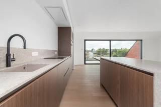 
In Destelbergen, verscholen in het groene Scheldeland en toch vlak bij het bruisende stadsleven, bevindt zich residentie Valeria: een kleinschalig project met tijdloze architectuur en oog voor detail. De residentie telt slechts 10 ruime BEN-appartementen, verdeeld over twee stijlvolle gebouwen, en beschikt achteraan over een groene privatieve tuin.<br />Binnen dit project wordt een unieke penthouse te koop aangeboden. Het appartement is ontworpen met maximale aandacht voor licht, ruimte en comfort en beschikt over een royaal zuidwestgericht terras waar u de hele dag door van de zon kunt genieten.<br />De afwerking is hoogwaardig en hedendaags. Er is onder meer een royale leefruimte met volledig ingerichte open keuken, een luxueuze badkamer met inloopdouche, twee slaapkamers, vloerverwarming met warmtepomp (inclusief koelfunctie), ventilatiesysteem D, parketvloeren en zonnewering. Ondergrondse parkeerplaatsen (niet inbegrepen) en bergingen zorgen voor extra gemak.<br />De ligging is een absolute troef. Winkels, scholen en bakkerijen bevinden zich op wandelafstand, terwijl u met de fiets in enkele minuten in hartje Gent staat. Voor ontspanning liggen het Reinaertpark en het natuurgebied Damvalleimeer vlakbij. Via de R4 zijn ook Antwerpen en Brussel vlot bereikbaar.<br />Goed nieuws: dit project komt in aanmerking voor het verlaagd BTW-tarief van 6%. <br />Een instapklaar pareltje voor wie kiest voor kwaliteit, duurzaamheid en een toplocatie.