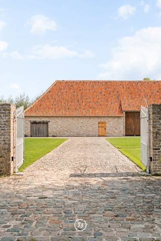 Deze karaktervolle fermette in Gistel bevindt zich op een ruim perceel van 5.202 m² en combineert een solide woning met een grote, veelzijdige schuur. Het hoofdhuis werd gebouwd in 2010 en vormt vandaag een uitstekende basis voor wie de eigendom verder naar eigen smaak wil afwerken en moderniseren.<br /><br />Hoewel het interieur op bepaalde vlakken een update kan gebruiken, werd bij de bouw gekozen voor kwalitatieve en duurzame materialen. Zo beschikt de woning onder meer over volle eiken parketvloeren en deuren en een bijzonder stevige constructie. Op het gelijkvloers bevinden zich de inkomhal met gastentoilet, living, eetruimte, veranda, keuken, mudroom/bijkeuken, badkamer en een slaapkamer.<br /><br />De verdieping is momenteel één grote open ruimte en biedt daardoor bijzonder veel potentieel. Met een doordacht ontwerp kunnen hier eenvoudig meerdere bijkomende slaapkamers en één of meerdere badkamers worden gerealiseerd. De oppervlakte laat minstens twee bijkomende slaapkamers toe, maar biedt voldoende ruimte om desgewenst tot vier kamers op deze verdieping te creëren. Hierdoor kan de woning volledig worden afgestemd op de noden van de toekomstige eigenaar.<br /><br />Een bijkomende troef is de grote vrijstaande schuur. Ook deze werd aan de buitenzijde vernieuwd, met onder meer een nieuw dak en vernieuwde muren. De ruimte kan vandaag dienstdoen als ruime garage of opslagplaats, maar biedt eveneens interessant toekomstpotentieel als bureel of praktijkruimte.<br /><br />Buiten sluit een zuidgericht terras aan op de woning, waar dankzij de ligging ook ’s avonds nog van de zon kan worden genoten. Alle aanwezige gebouwen en verhardingen zijn vergund.<br /><br />Een eigendom met een sterke basis, kwalitatieve materialen en vooral veel mogelijkheden voor wie op zoek is naar ruimte en flexibiliteit en de laatste afwerking graag naar eigen hand zet.