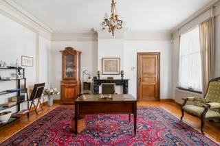 Achter deze statige gevel schuilt een uitzonderlijke herenwoning met een bewoonbare oppervlakte van maar liefst 546 m². Authentieke elementen werden doorheen de woning met zorg bewaard en versterken het unieke karakter van deze eigendom. De royale volumes, dubbele toegang en flexibele indeling maken deze eigendom uitermate geschikt voor wie op zoek is naar een ruime gezinswoning, een combinatie van wonen en werken of een eigendom met uiteenlopende gebruiksmogelijkheden.<br /><br />De woning maakt deel uit van het beschermde stadsgezicht ‘Vredeberg’ en is opgenomen als bouwkundig erfgoed. Hierdoor is de residentiële renovatieverplichting niet van toepassing.<br /><br />Via de centrale inkomhal bereikt u de bureau- of praktijkruimte, de ruime eetkamer en de lichtrijke leefruimte met een prachtig groen zicht op de privatieve tuin van 185m². De afzonderlijke keuken biedt alle ruimte en comfort voor dagelijks gebruik. Op het gelijkvloers bevinden zich verder een slaapkamer of polyvalente ruimte met ingemaakte kasten, een gastentoilet, berging, wasruimte, toegang tot de droge kelder en een bijkomende binnenplaats van 25m².<br /><br />De onderhoudsvriendelijke mediterrane tuin vormt een rustige buitenruimte en geeft rechtstreeks toegang tot de dubbele garage met elektrische poort en extra opbergruimte, bereikbaar via het Vlietje.<br /> <br />De eerste verdieping is bereikbaar via de statige trappenhal of comfortabel met de lift, die eveneens toegankelijk is via de tweede inkomdeur. Hier bevinden zich vier volwaardige slaapkamers, waarvan één met een ensuite badkamer voorzien van douche, bidet en dubbel lavabomeubel. Daarnaast is er een tweede badkamer met ligbad, toilet en lavabomeubel.<br /> <br />Een absolute troef is de voormalige tandartspraktijk op de tweede verdieping. Met een oppervlakte van maar liefst 177 m² biedt deze verdieping uitzonderlijk veel potentieel voor extra woonruimte, een praktijk, atelier of een andere invulling. Aansluitend bevinden zich nog twee ruime zolderverdiepingen, die bijkomende mogelijkheden bieden.