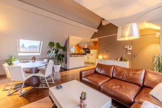 Dit appartement is gelegen op wandelafstand van het centrum, wat zorgt voor een uitstekende bereikbaarheid. Daarnaast bevindt het appartement zich nabij alle faciliteiten (winkels, restaurants, recreatieve voorzieningen, groot parkingplein...) waardoor het een ideale plek is om te wonen voor mensen die op zoek zijn naar het gemak van stadsleven.<br />INDELING:<br />U bereikt het dakappartement met lift of trap. De woonkamer met open ingerichte keuken werd praktisch ingedeeld met eet- en zithoek en geniet van natuurlijk lichtinval. De open keuken is uitgerust met een ijskast,, kookplaat, dampkap, combi-oven, vaatwasser en wastafel. Langs de keuken is een handige berging/wasplaats voorzien. Vanuit de woonkamer hebt u toegang tot een zeer groot, gezellige terras. Via de nachthal met ingemaakte kastenwand ga je naar de 2 slaapkamers met ingemaakte kasten De badkamer is voorzien van een douchecabine, toilet en badkamermeubel.<br />Verder uniek aan dit appartement: er is een zolder die toelaat om veel spullen op te bergen.<br />Extra: - Verlichting in woonkamer aanwezig, <br />- Op het gelijkvloers is een gemeenschappelijke fietsenstalling.